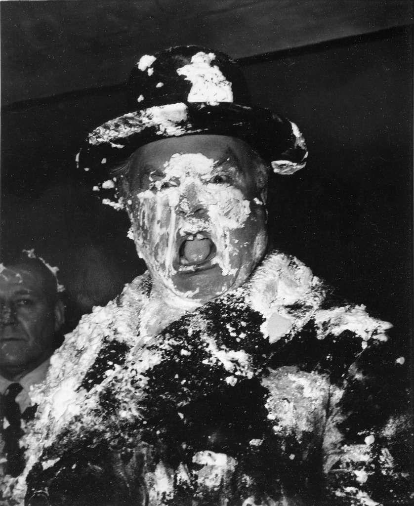 A man's face is covered in cream as a result of a pie fight in