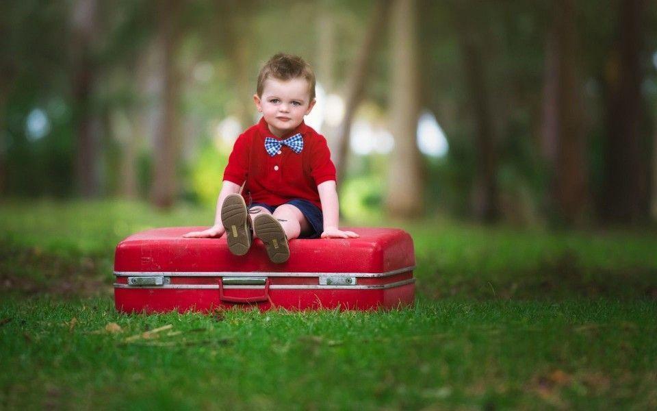 Cute Baby Boy Sitting On Red Suitcase Wallpaper
