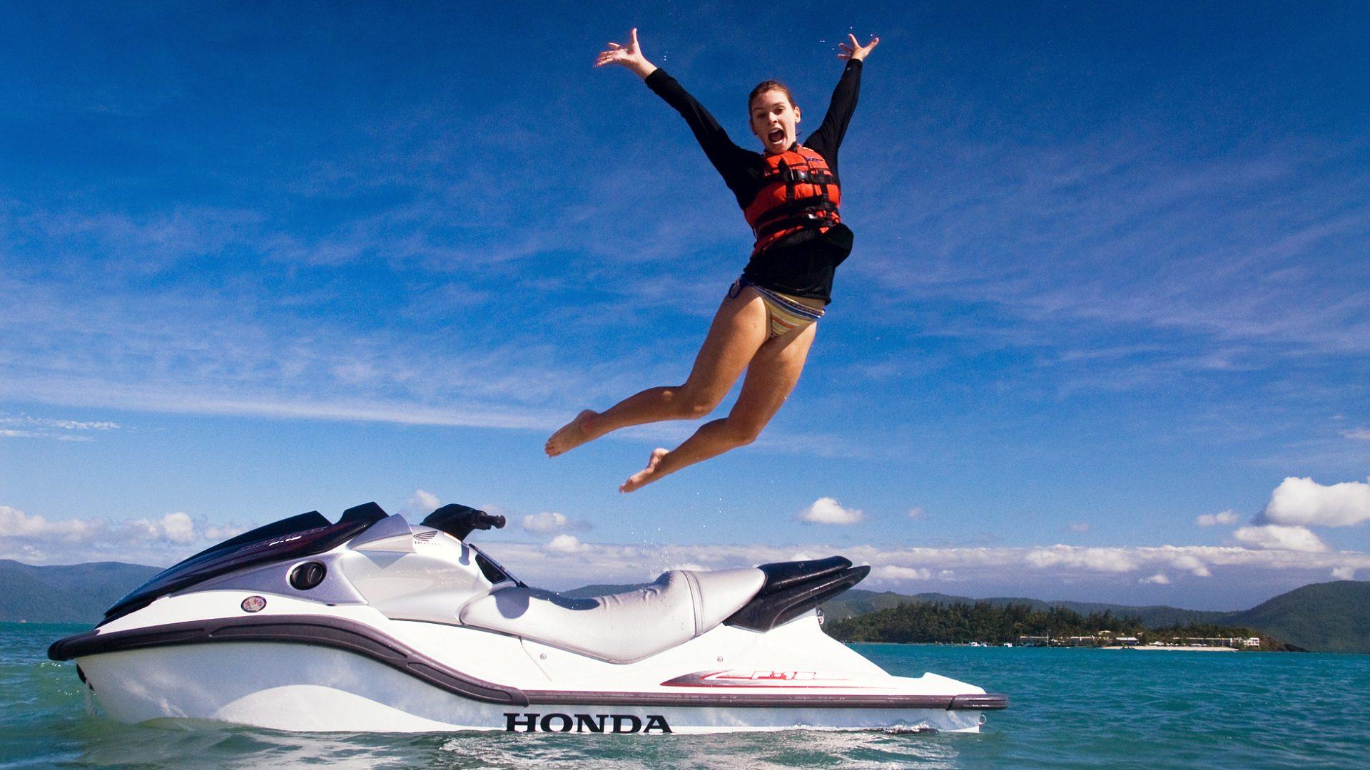 High Definition Wallpaper Of A Woman Jumping Out Of A Jetski