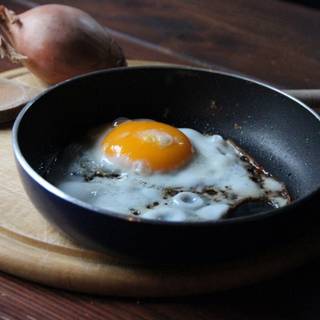 ou prăjit cu partea însorită în sus într-o tigaie lângă ceapă