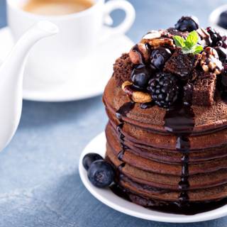 Stack of chocolate pancakes with sauce and toppings