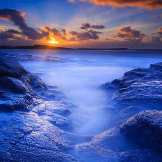 Sunrise over blue rocky seashore