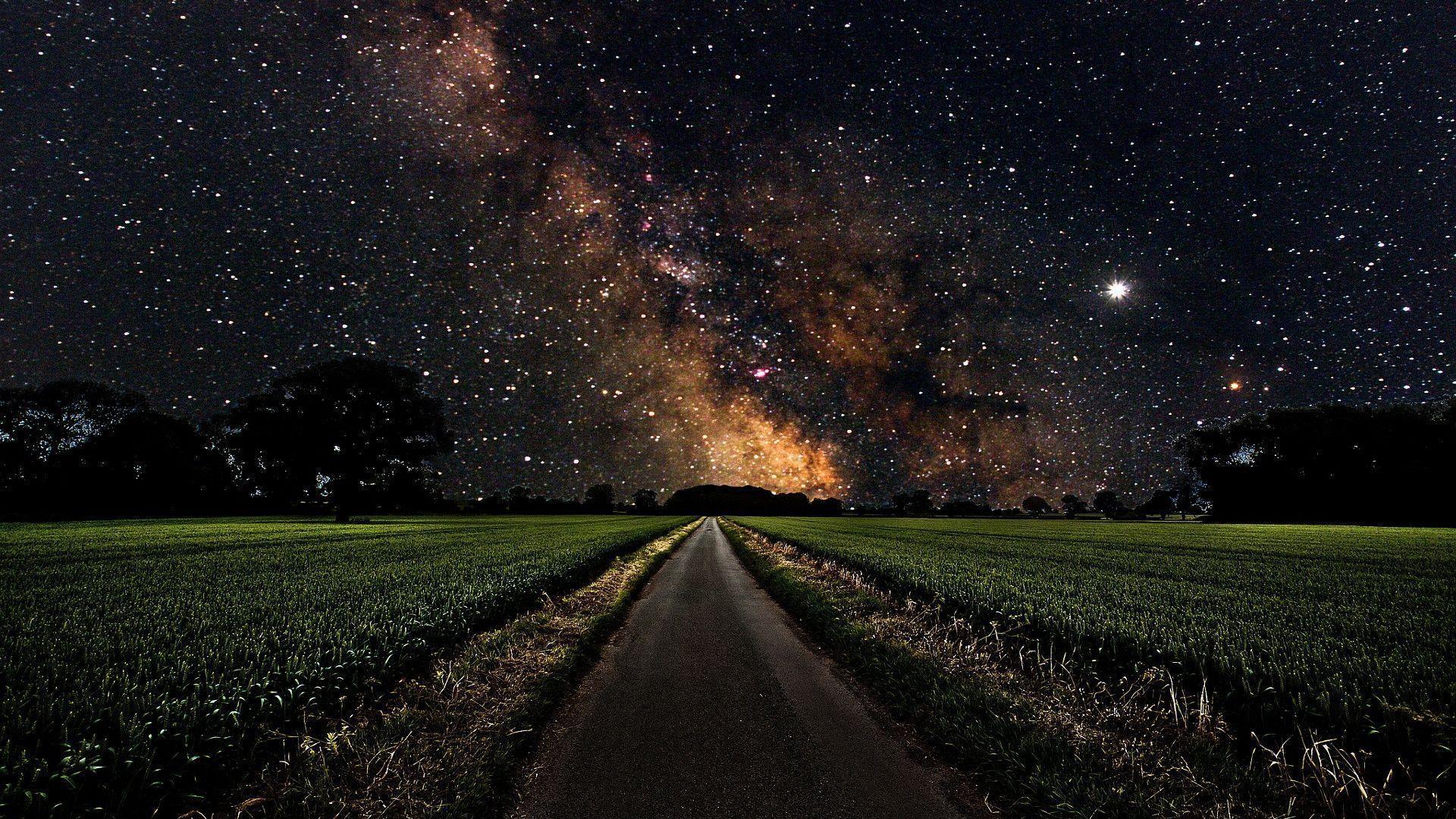 Milky Way over a green field wallpaper