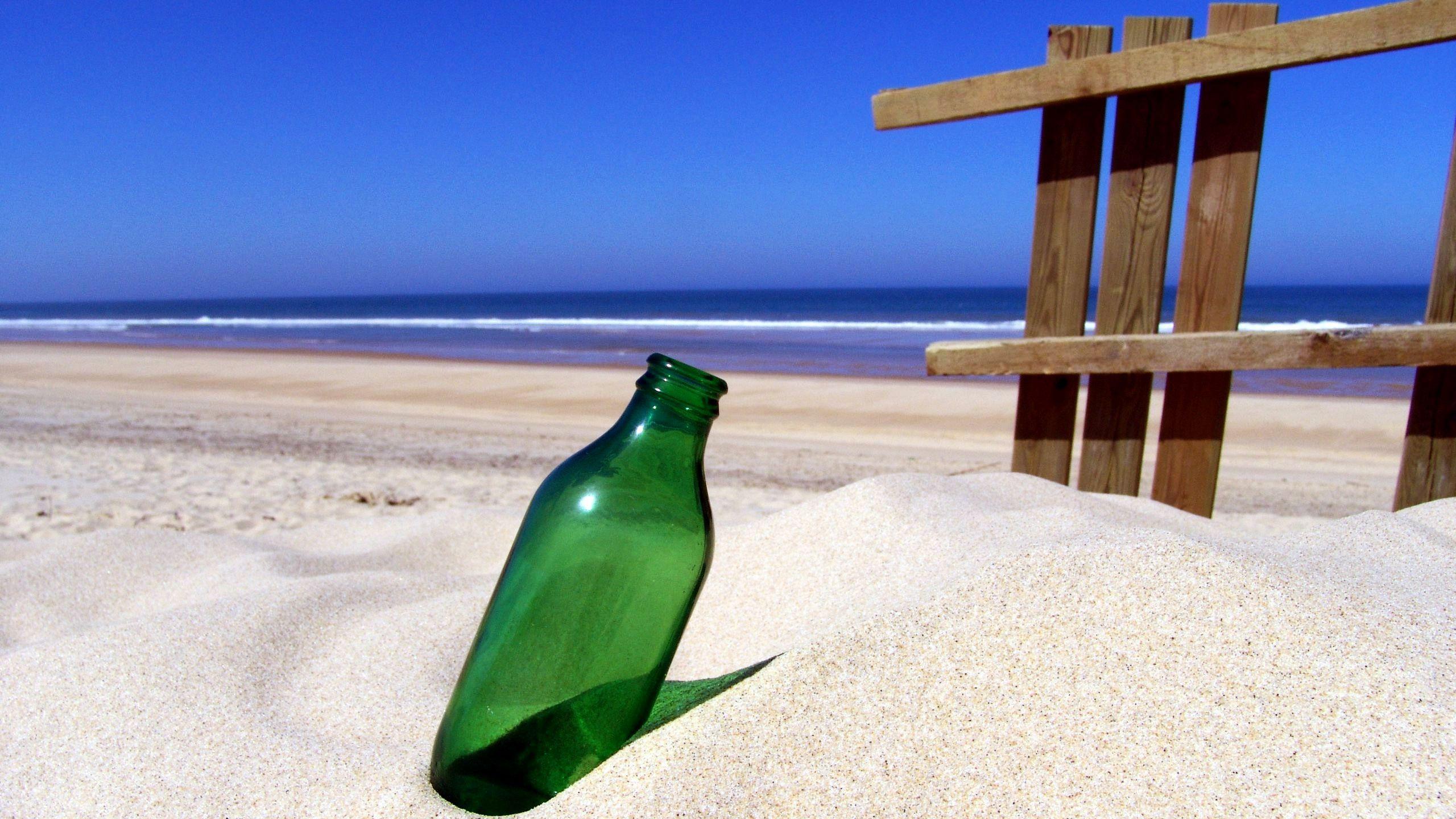 Green bottle on sandy beach wallpaper