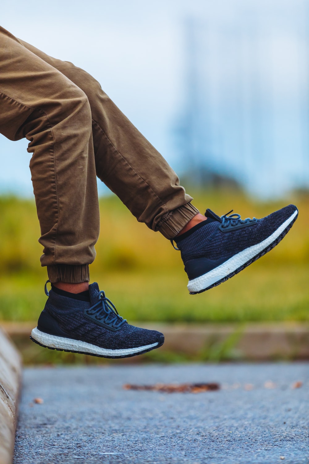 person wearing brown jogger pants and blue adidas running shoes during daytime photo