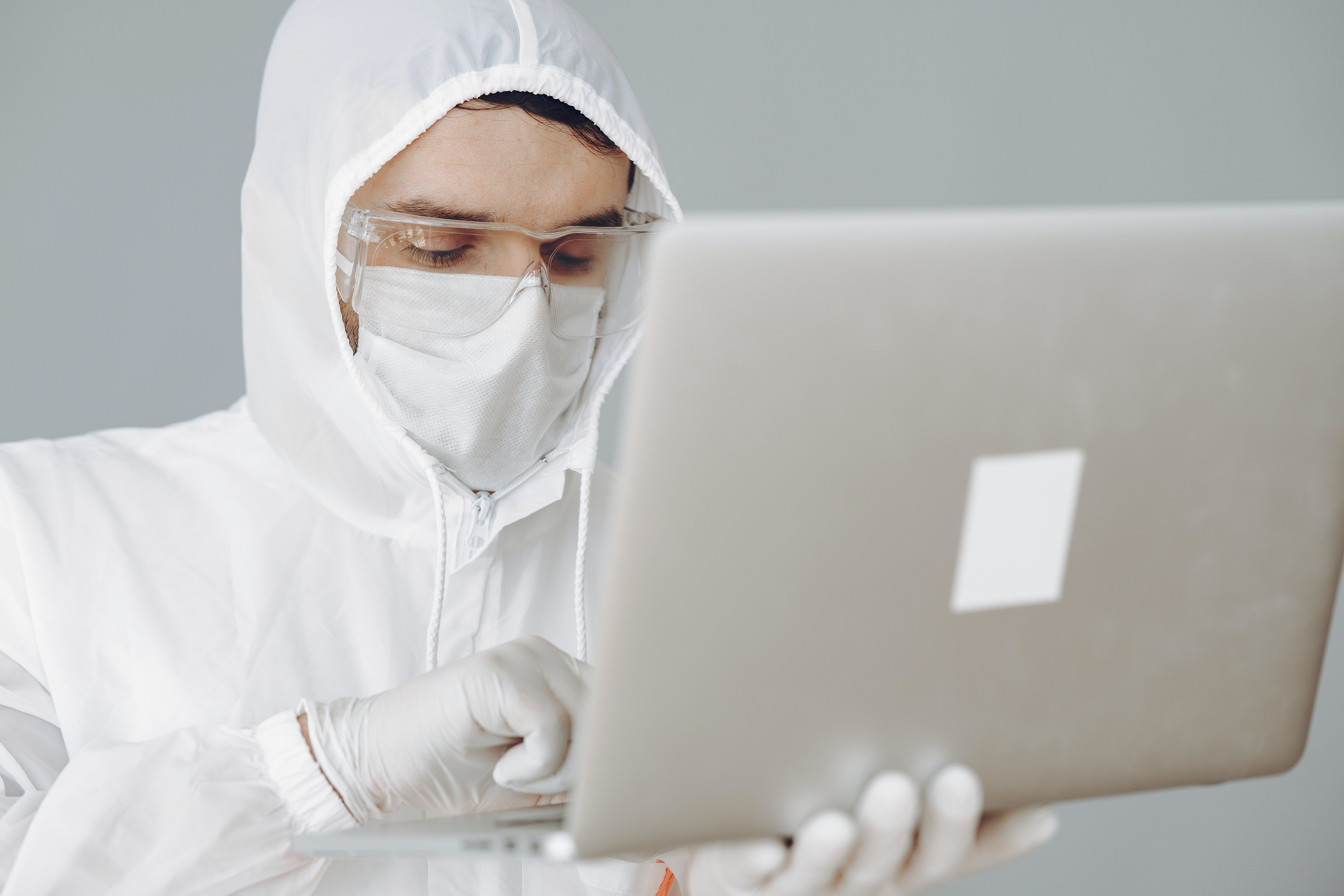 Photo of Person in Personal Protective Equipment Using MacBook · Free