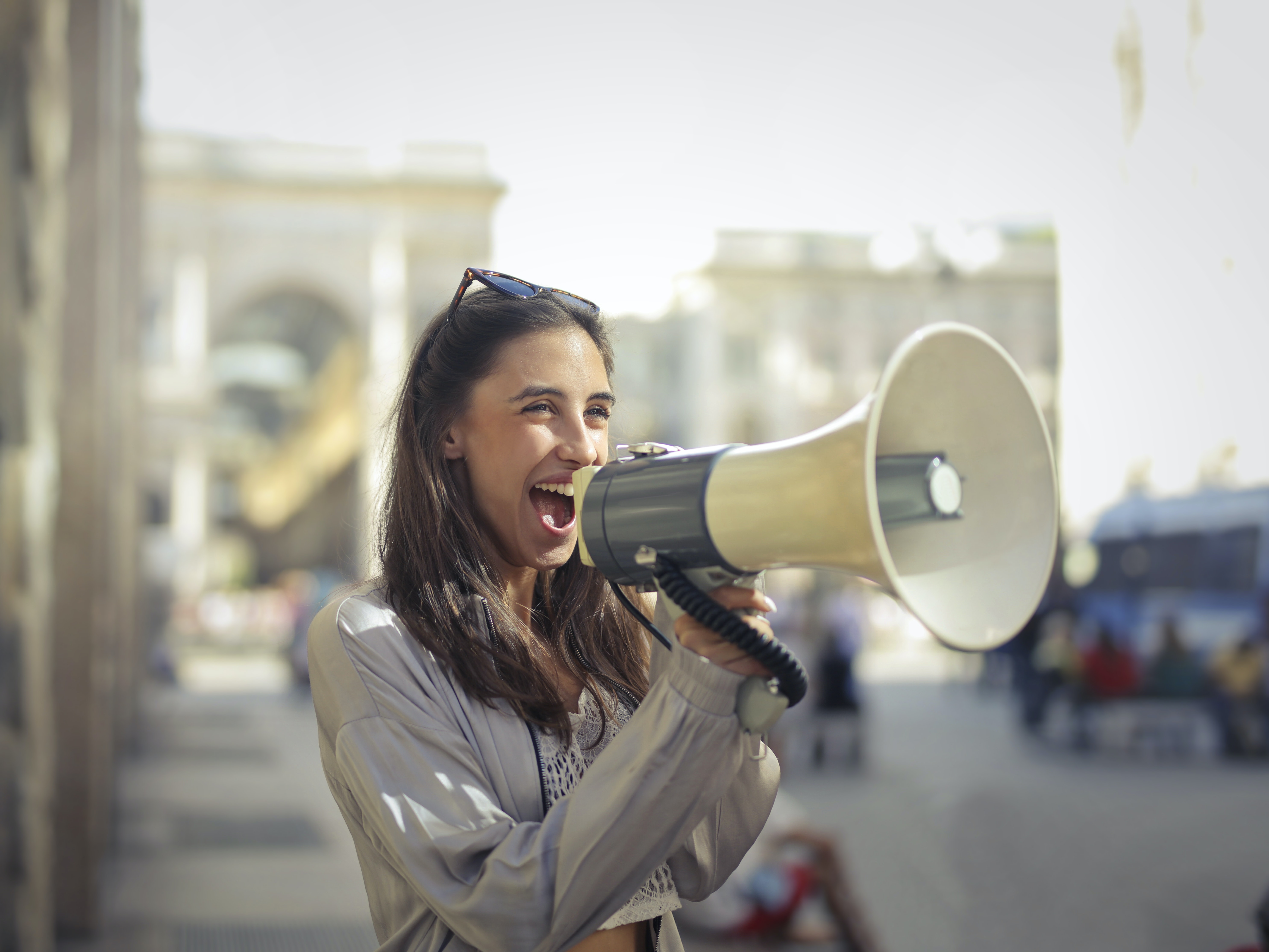 Cheerful young woman screaming into megaphone · Free