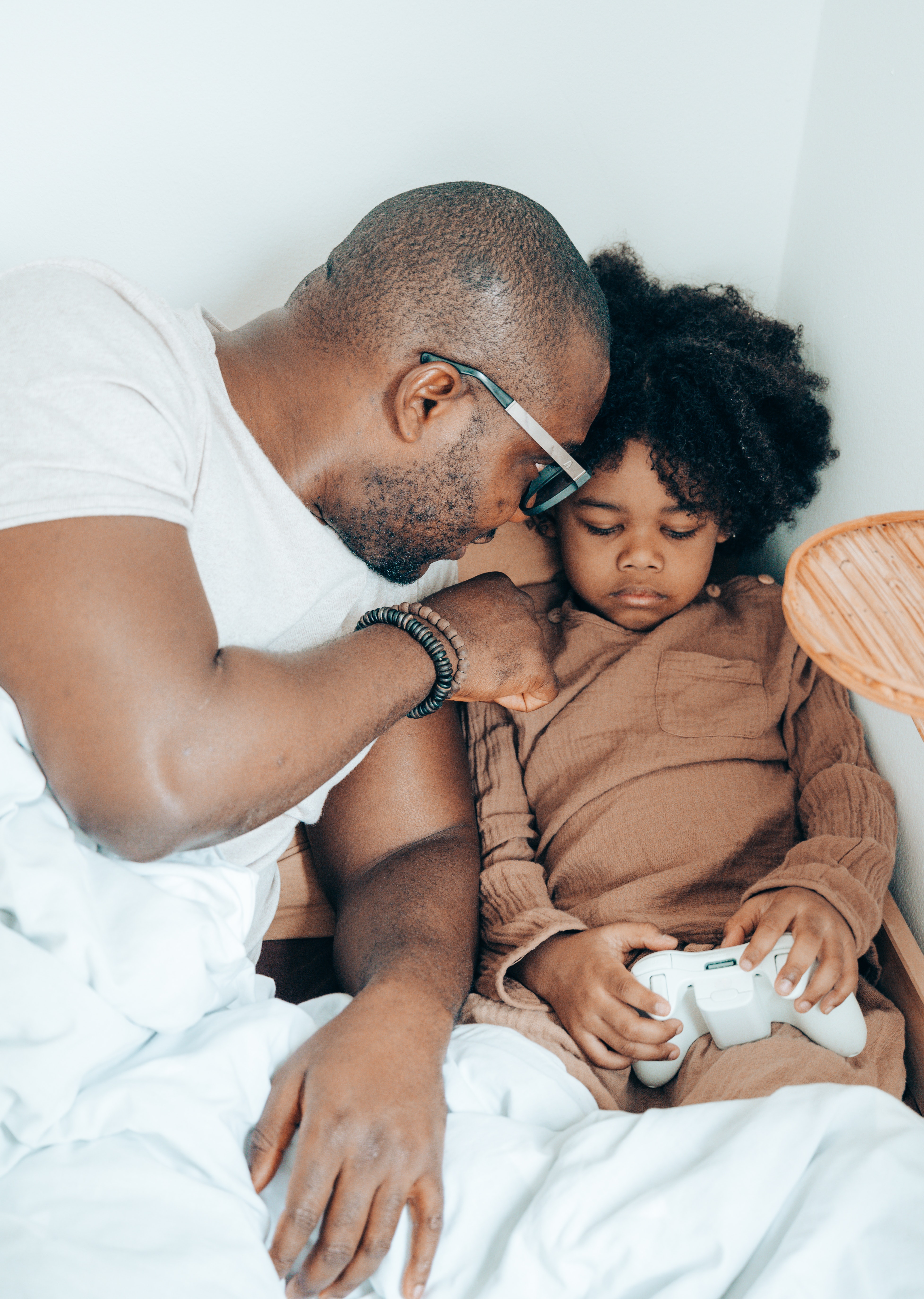Loving black father spending free time with cute daughter in bed at home · Free