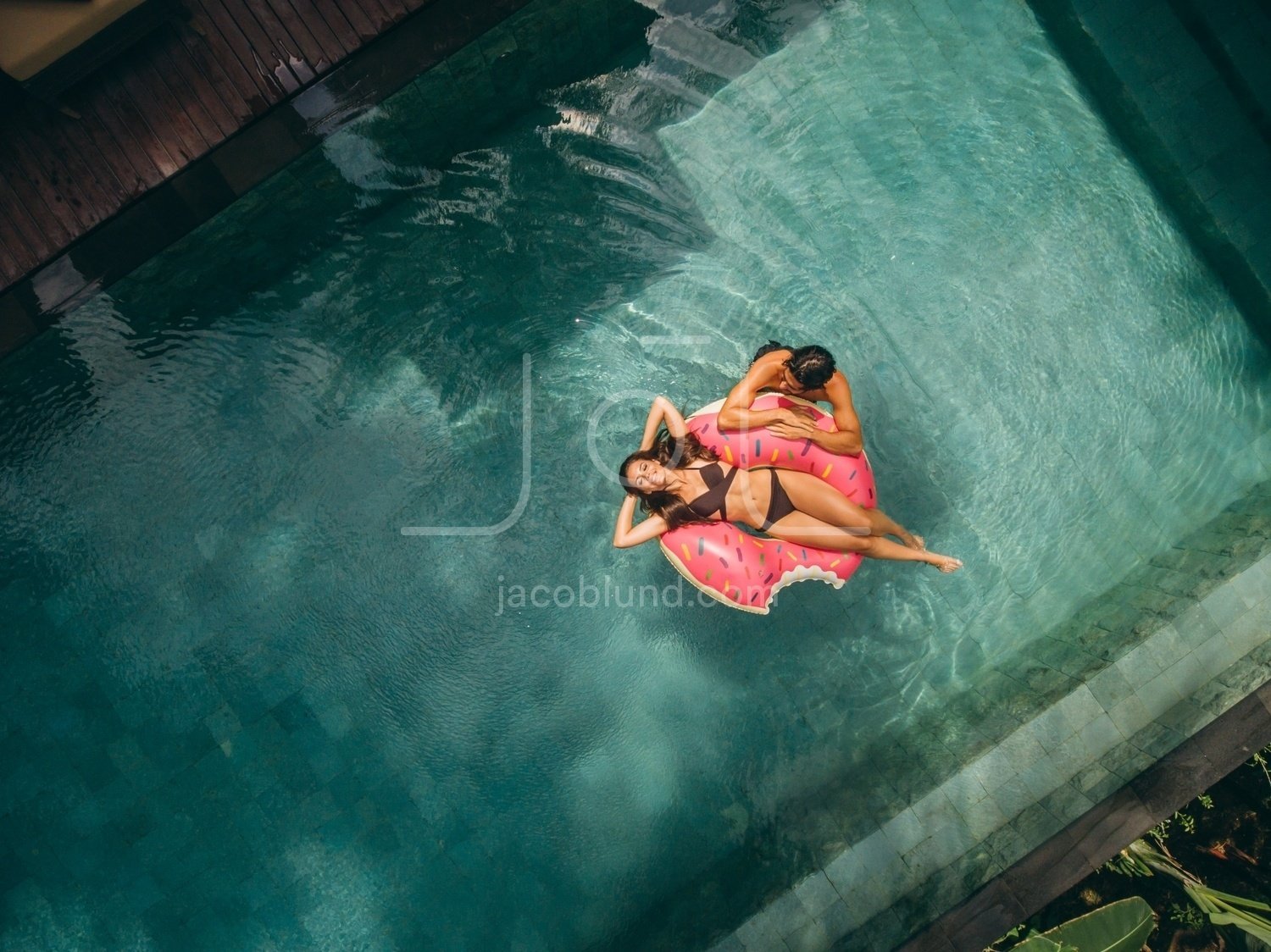 Couple relaxing on donut floatie in resort pool