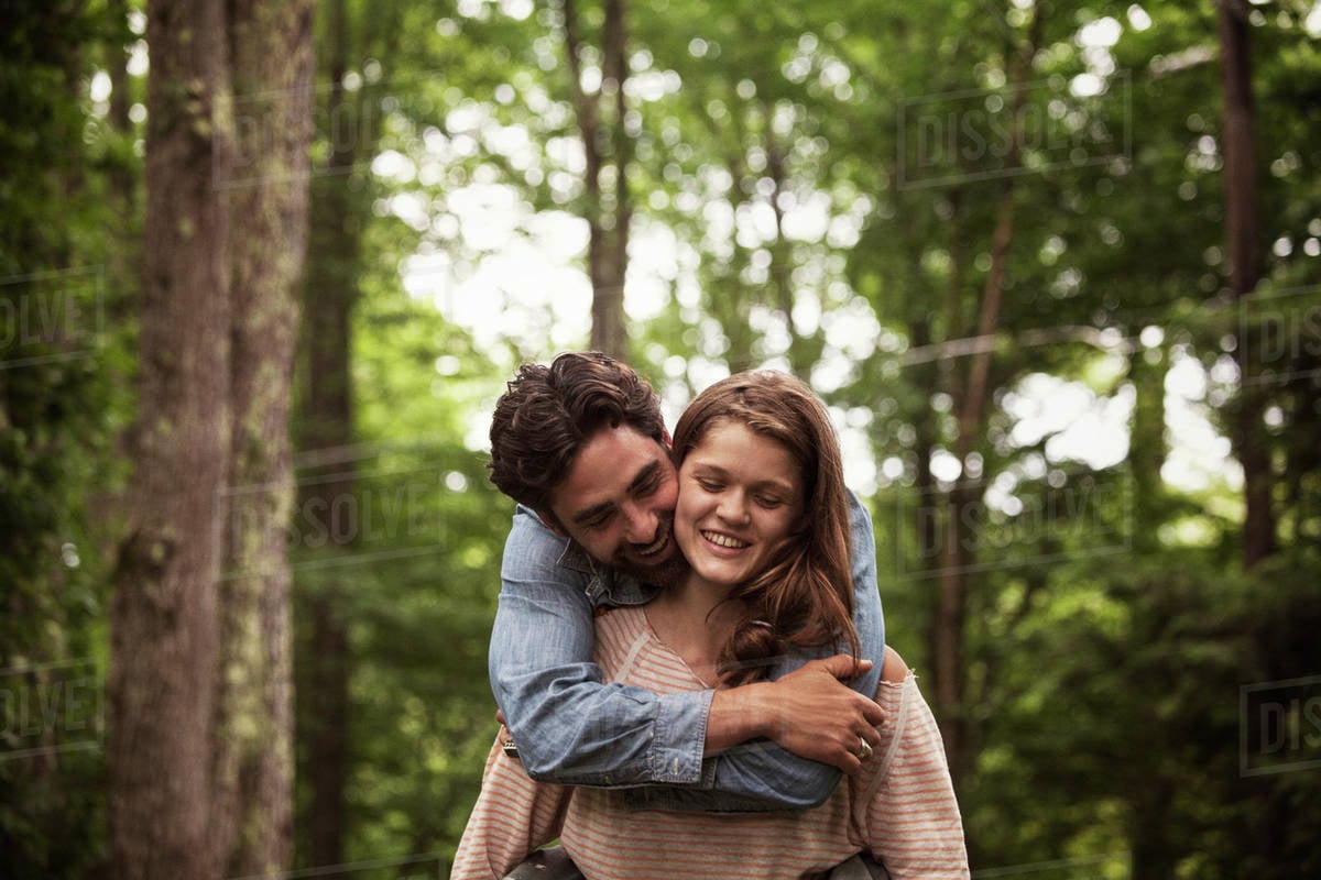 Young woman giving piggyback ride to her boyfriend in forest