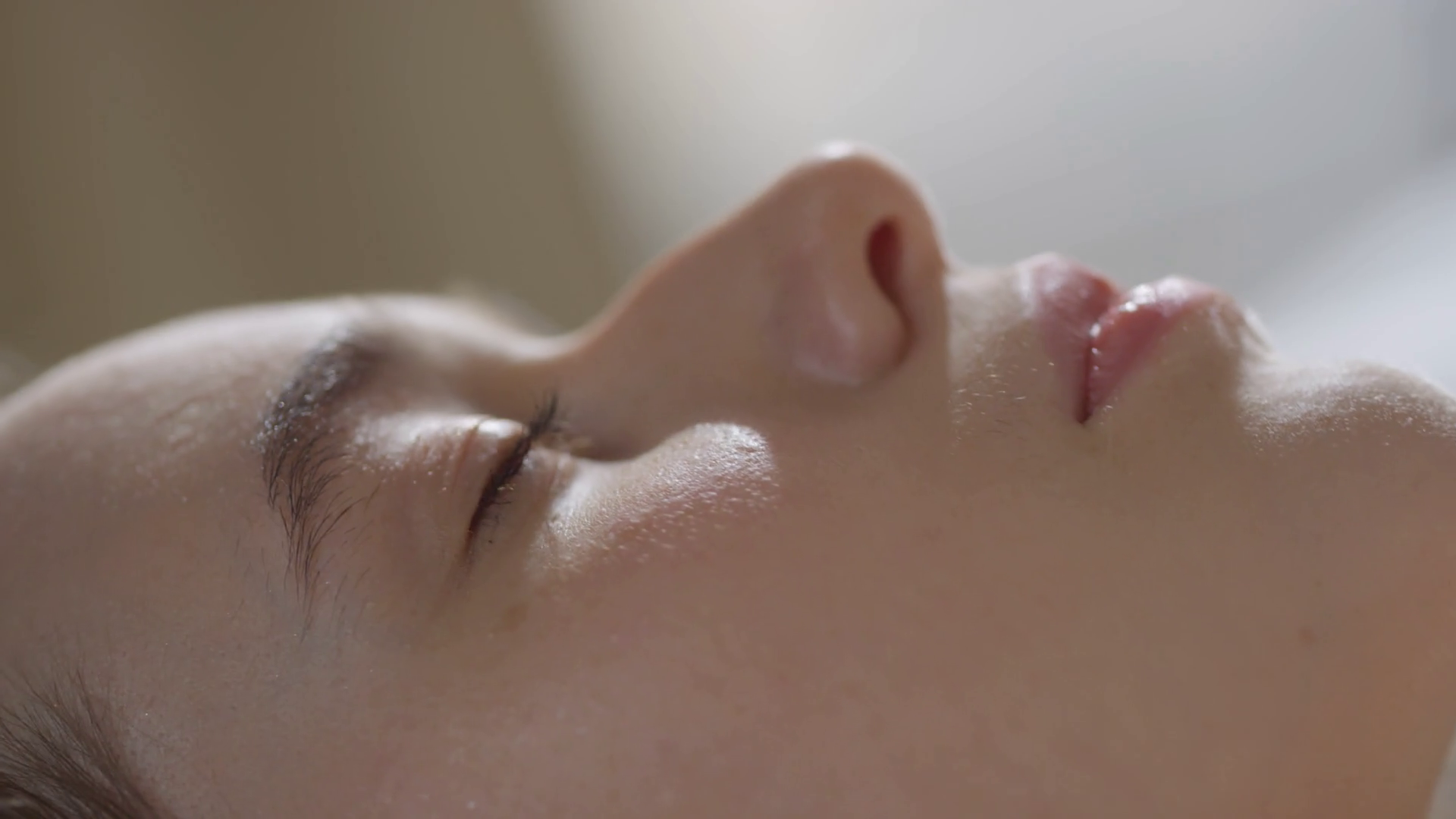Extreme close up shot with slowmo of face of beautiful young woman waking up in morning and blinking while looking away from camera Stock Video Footage