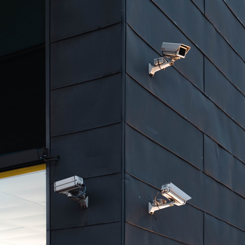three white CCTV camera on building wall photo