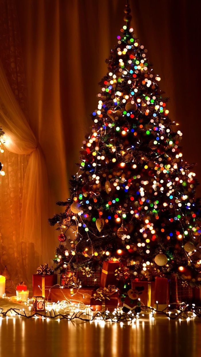 decorated christmas tree with lots of colorful lights merry christmas wallpaper presents underneath