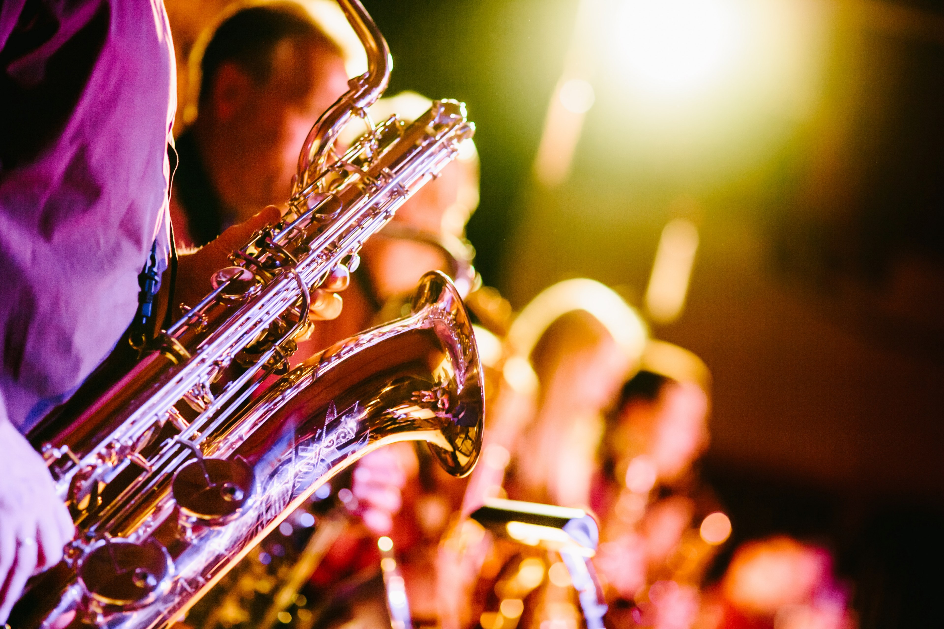 Wallpaper / a close up of a saxophone held by one of the band members during a jazz concert, colorful jazz concert 4k wallpaper
