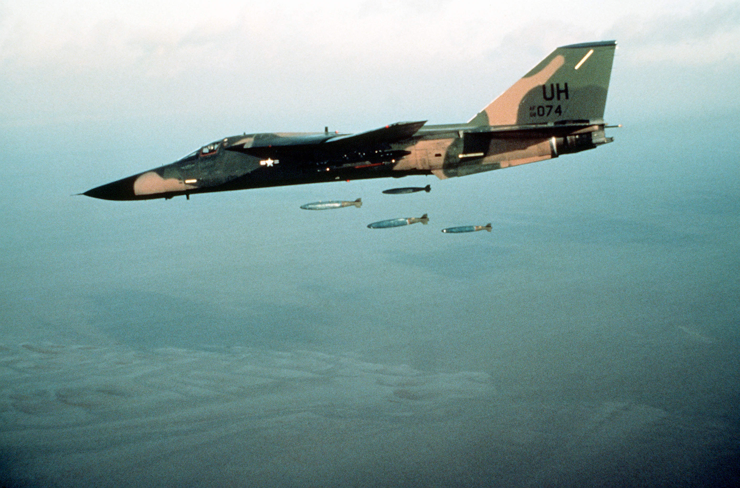 An Air To Air Left Side View Of A 20th Tactical Fighter Wing F 111E Aircraft Dropping Bombs Over A Range DF ST 87
