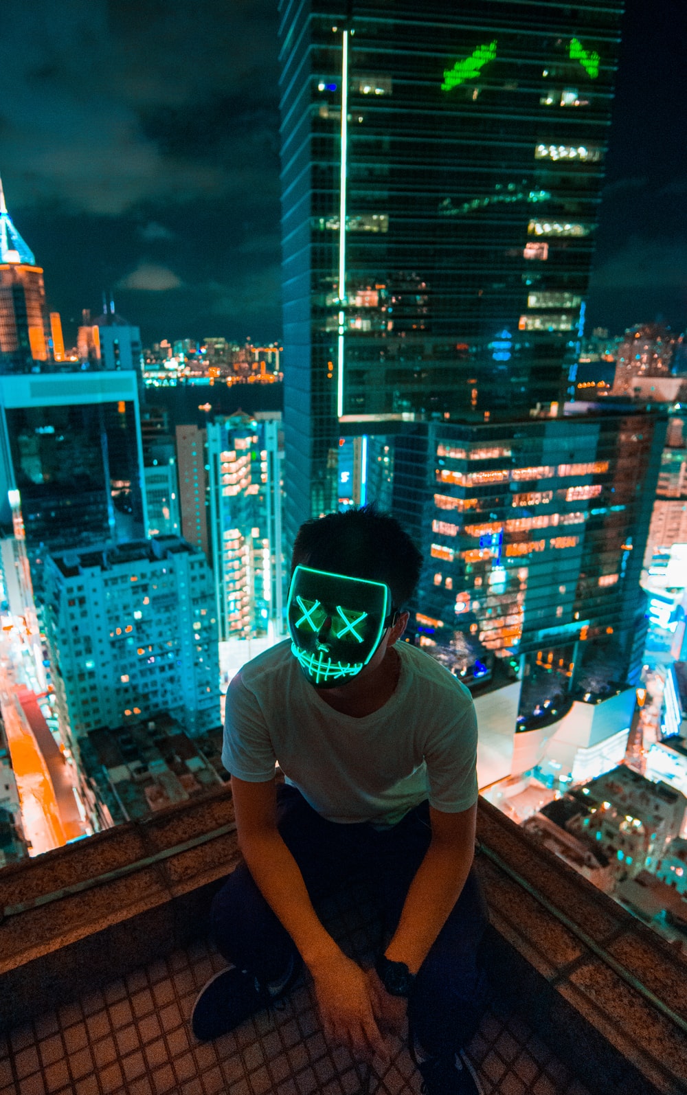 man wearing mask sitting on top of building photo