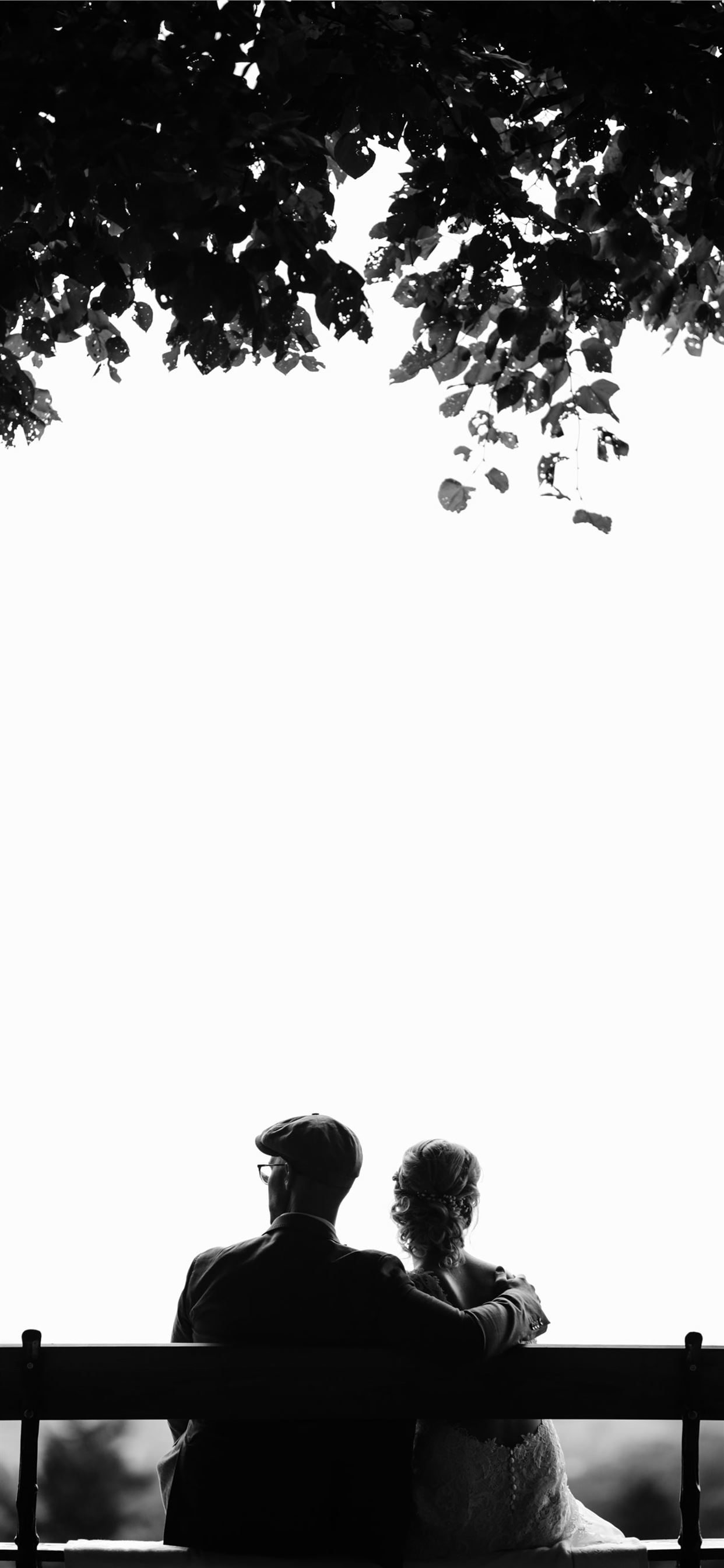 couple sitting on bench under tree grayscale photo. iPhone 11 Wallpaper Free Download