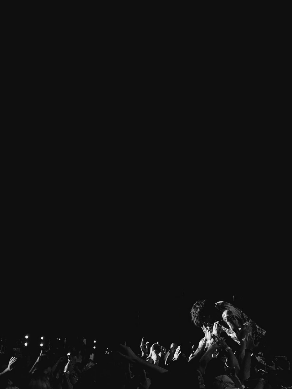 grayscale photograph of man in mosh pit photo