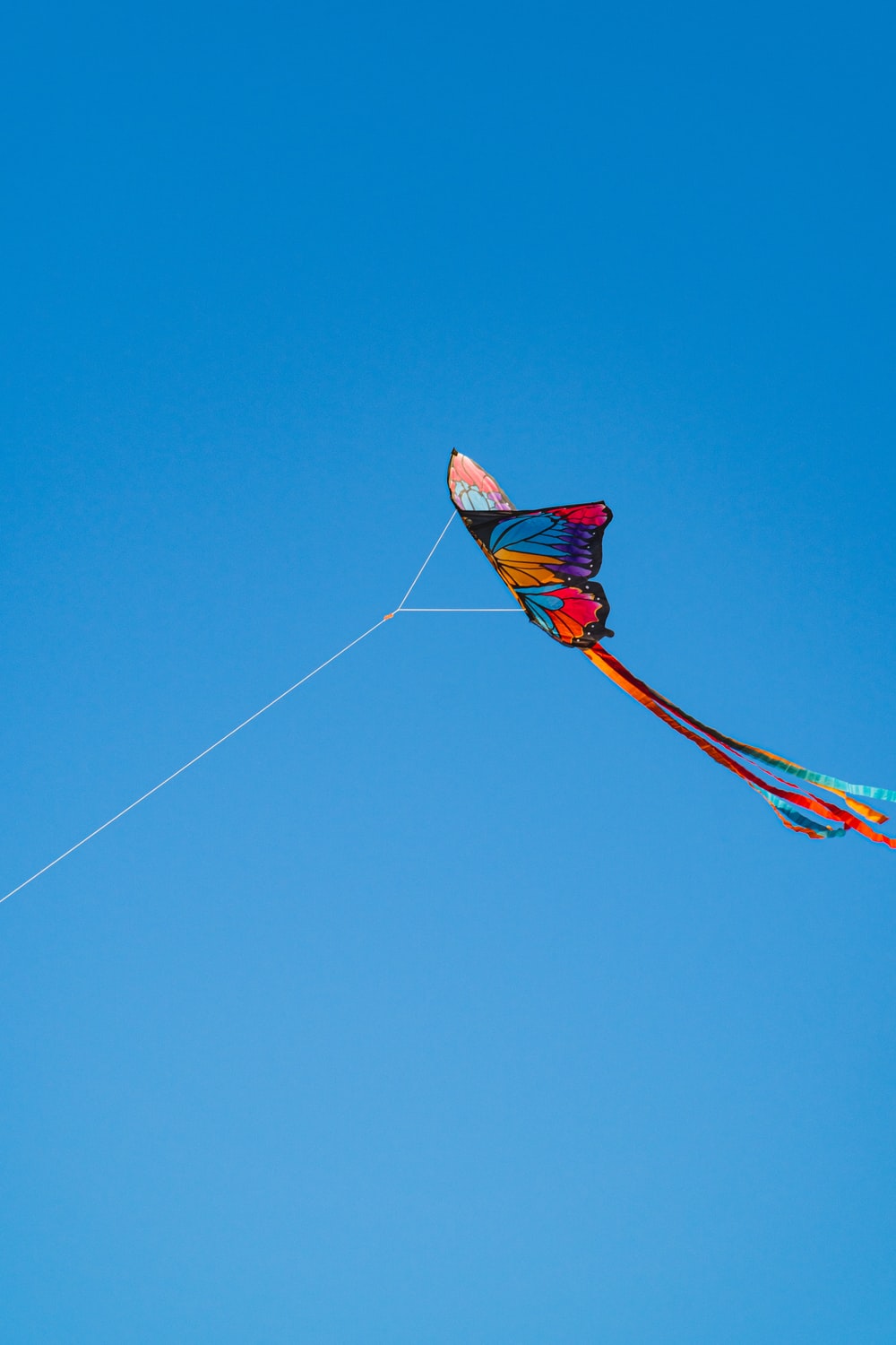 red and yellow kite flying under blue sky during daytime photo