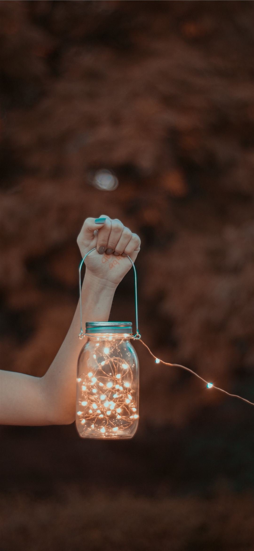 person holding mason jar with string lights iPhone Wallpaper Free Download