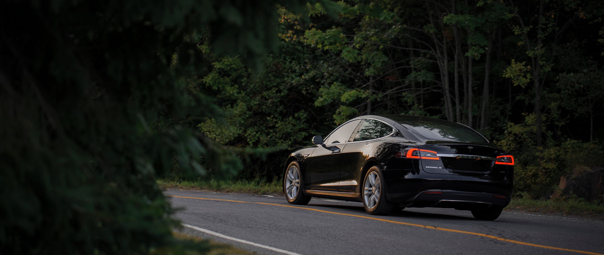 Download wallpaper 2560x1080 tesla, auto, black, side view, road dual wide 1080p HD background