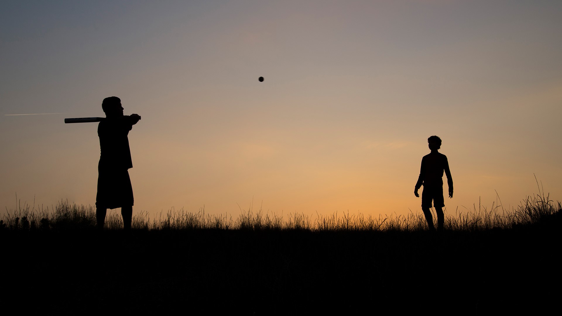 Silhouette of man and teenage boy playing baseball. Windows 10 Spotlight Image