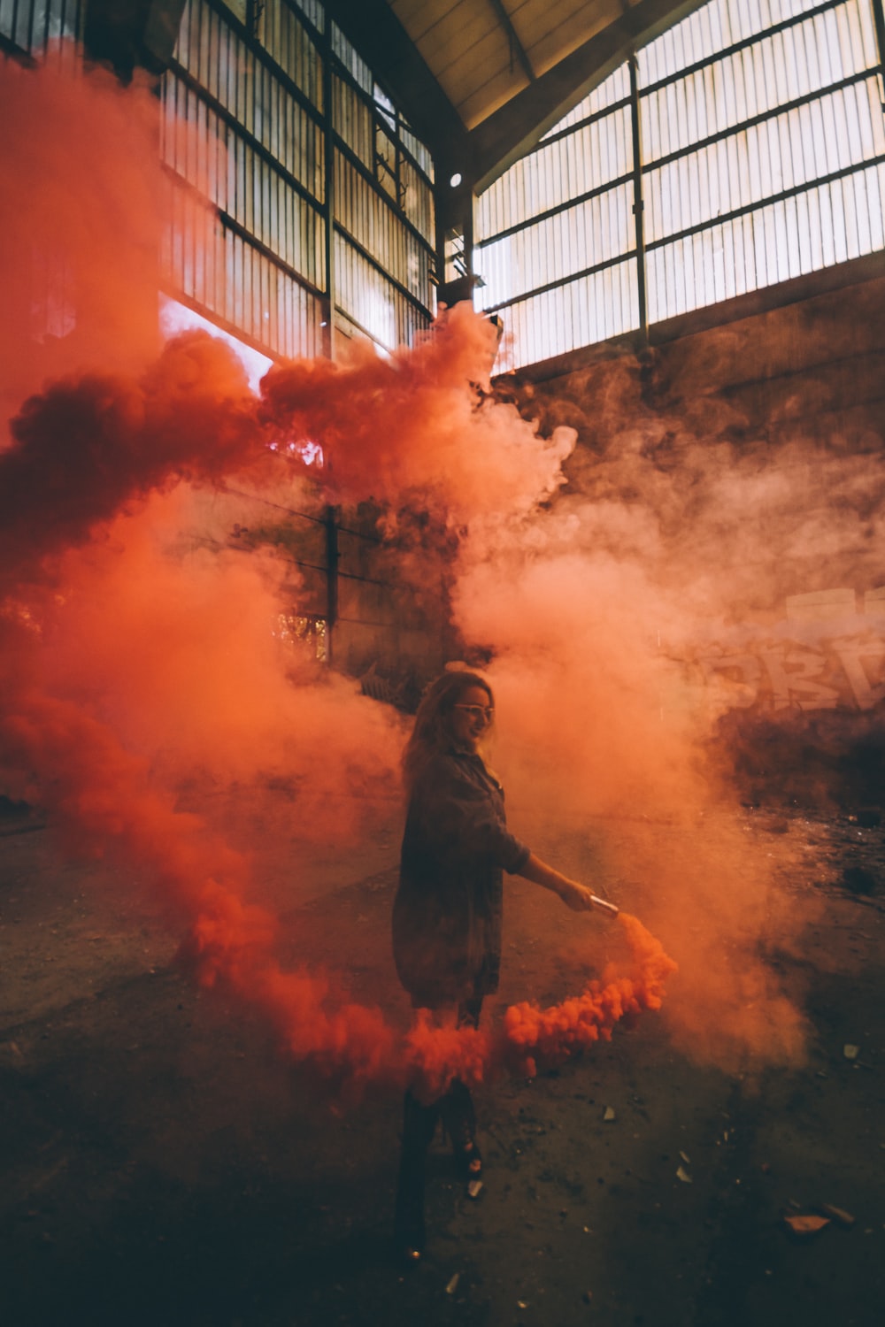 woman holding orange smoke bomb inside room photo