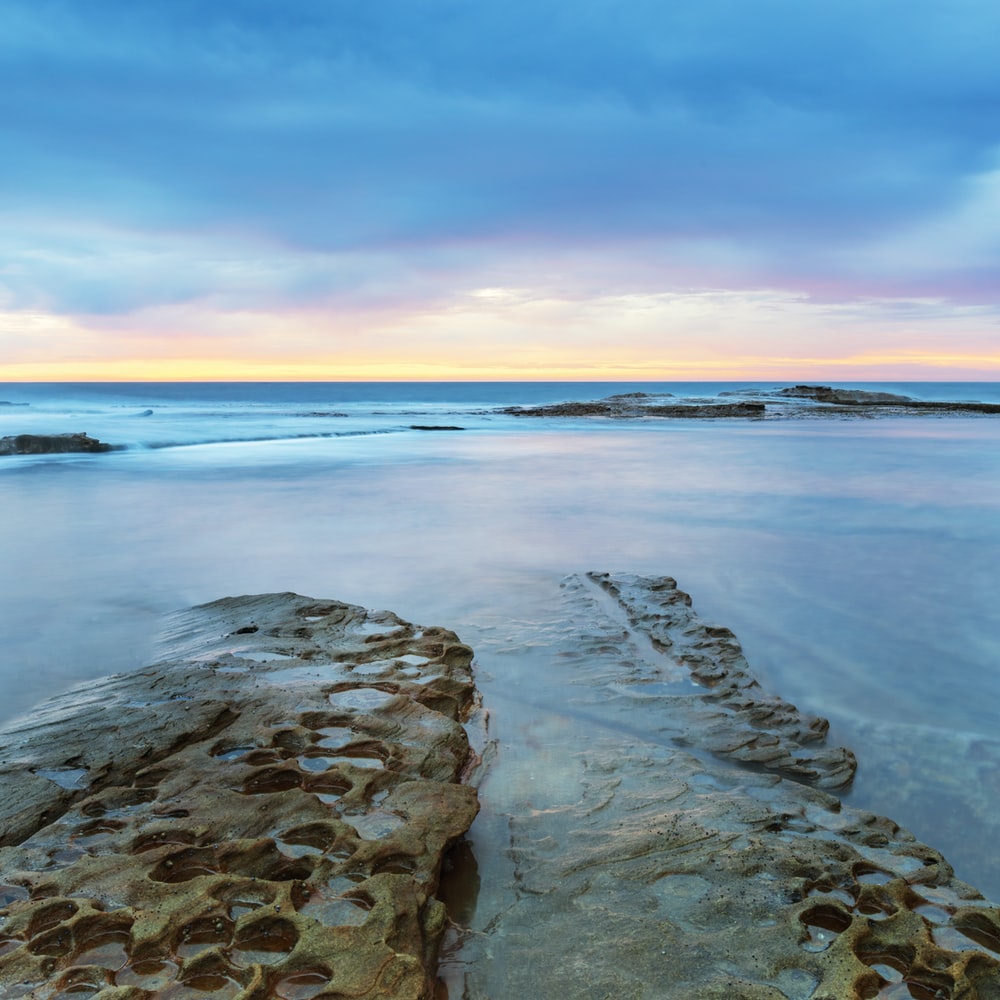 gray rocky shore during sunset photo