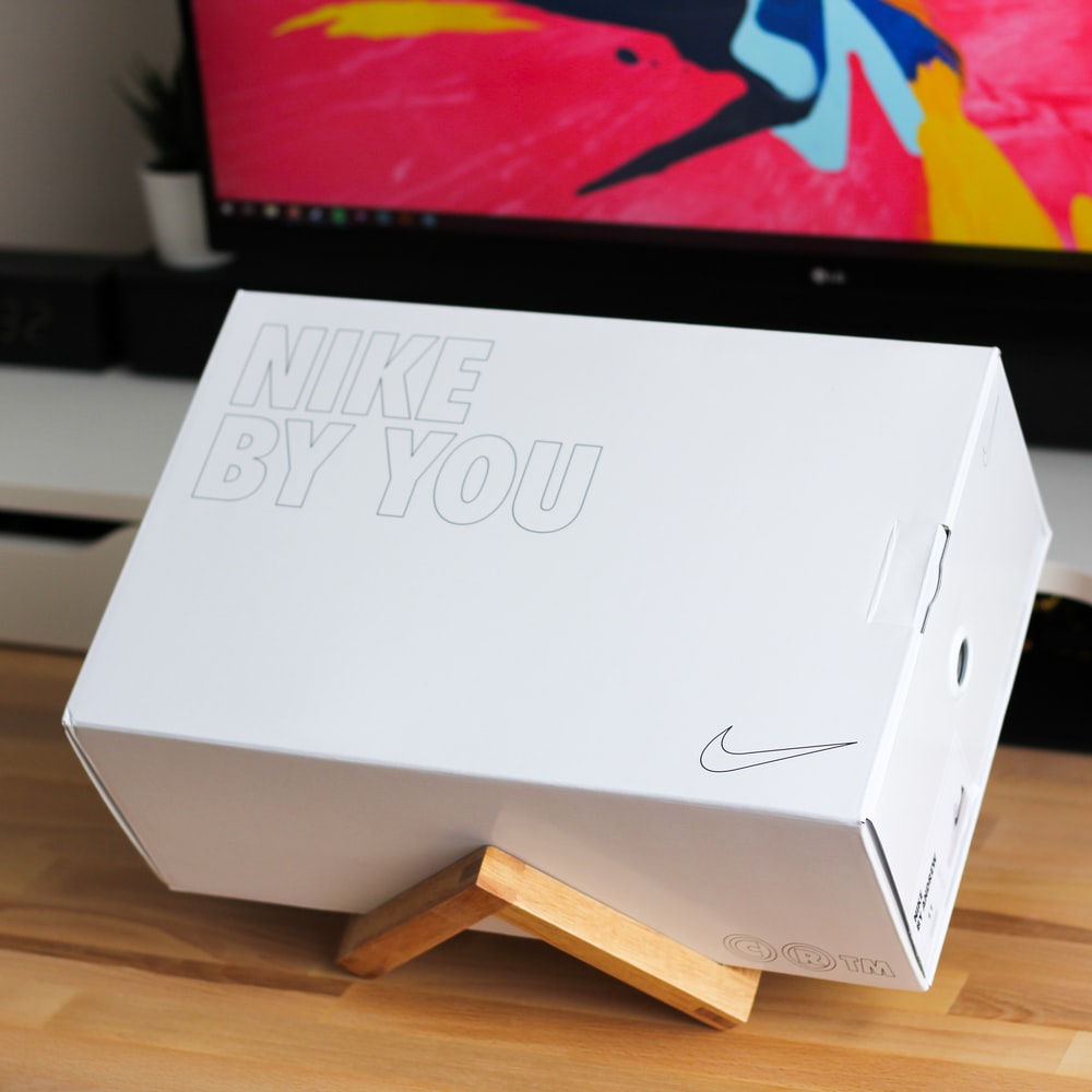 white Nike shoe box on brown wooden rack photo
