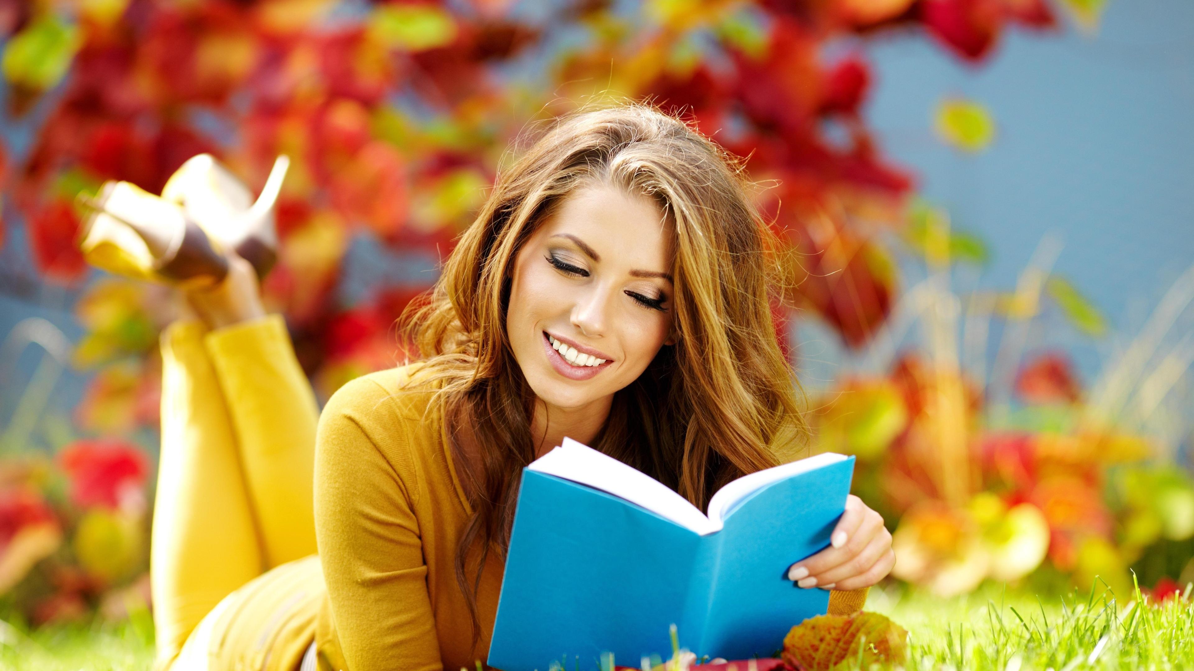 Girl in yellow reading a book on the grass in garden