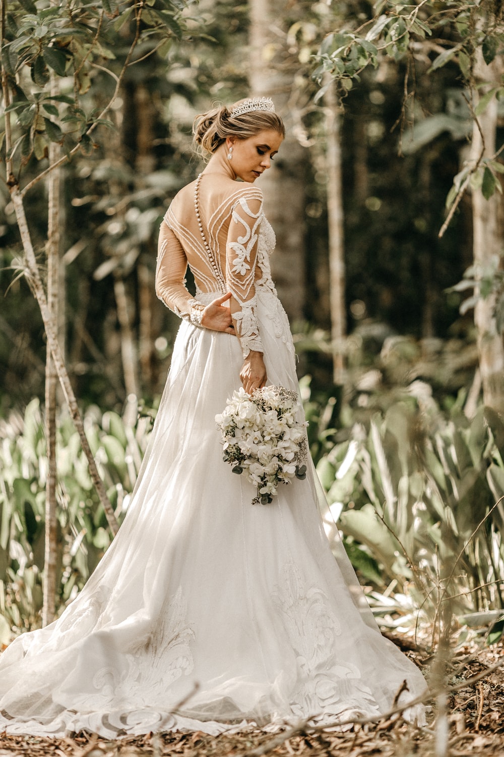 woman in white wedding dress standing on beach during daytime photo