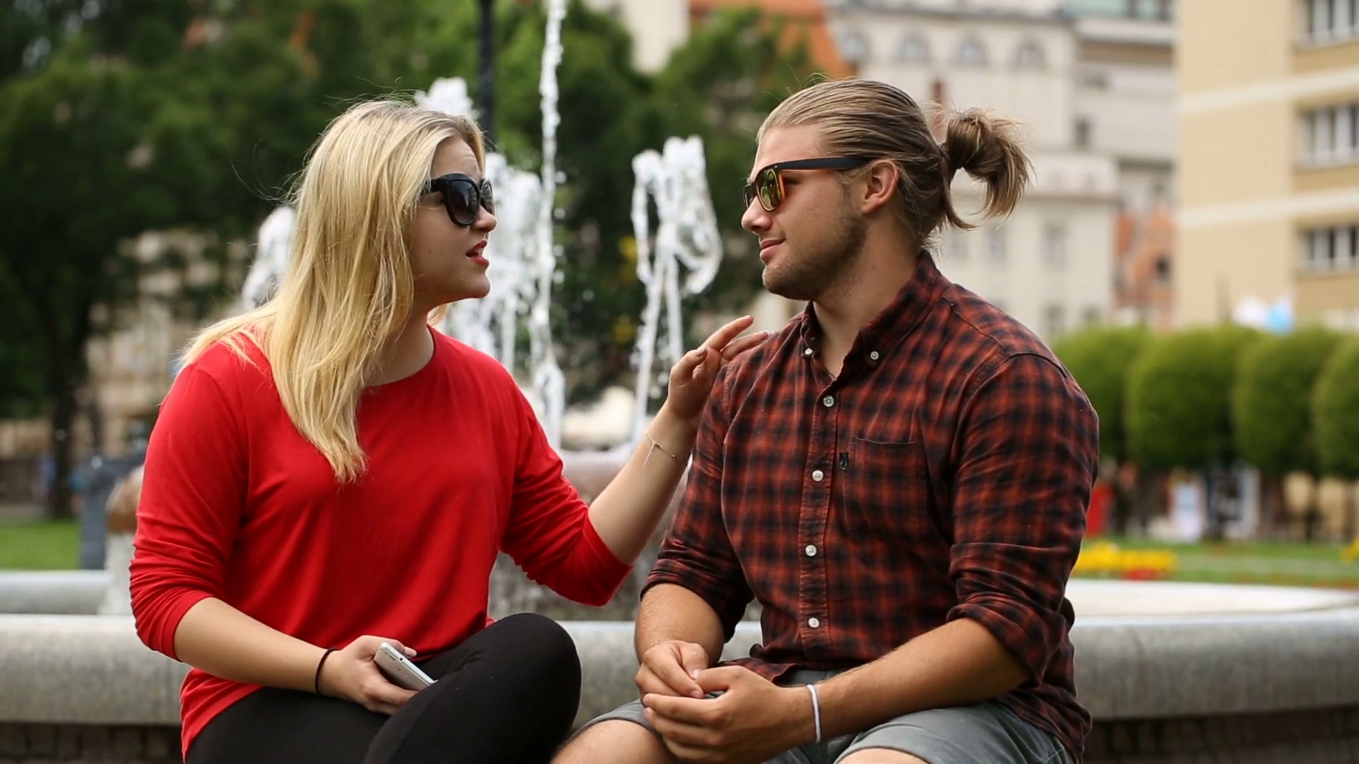Girl comforting her sad boyfriend while sitting next to the fountain Stock Video Footage