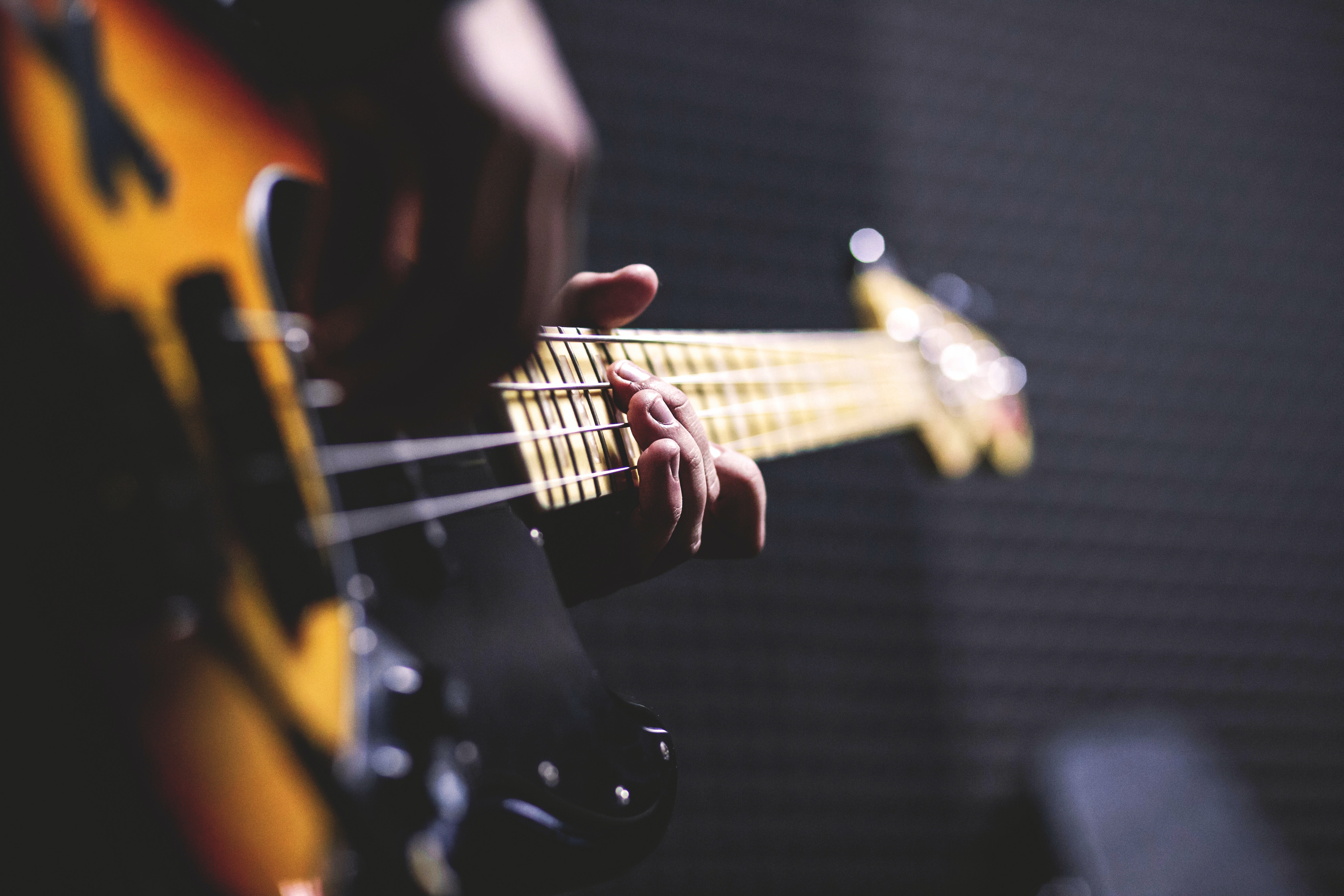 Person Playing Sun Burst Electric Bass Guitar in Bokeh Photography · Free