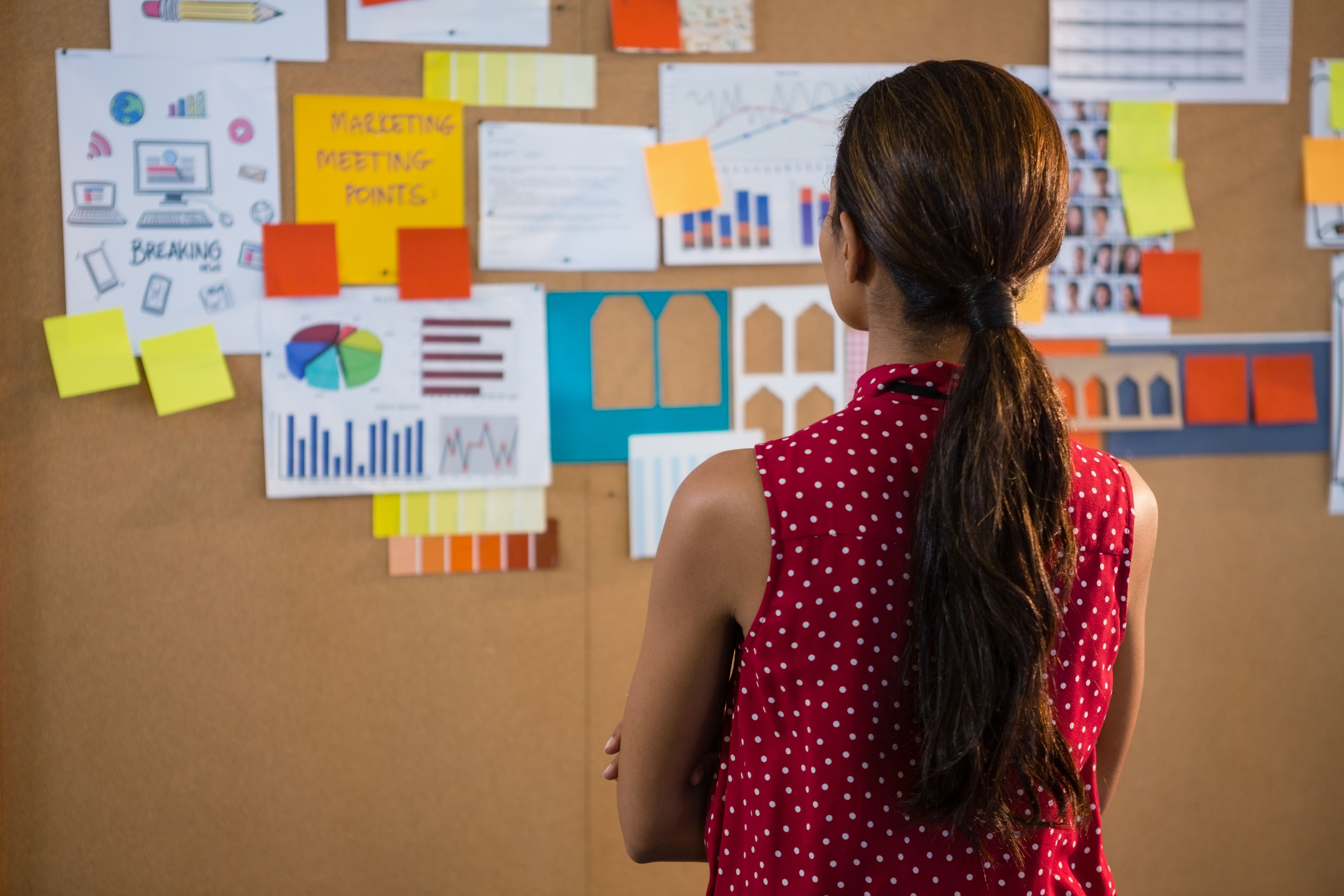 Female executive looking at the bulletin board in office Photo from PikWizard