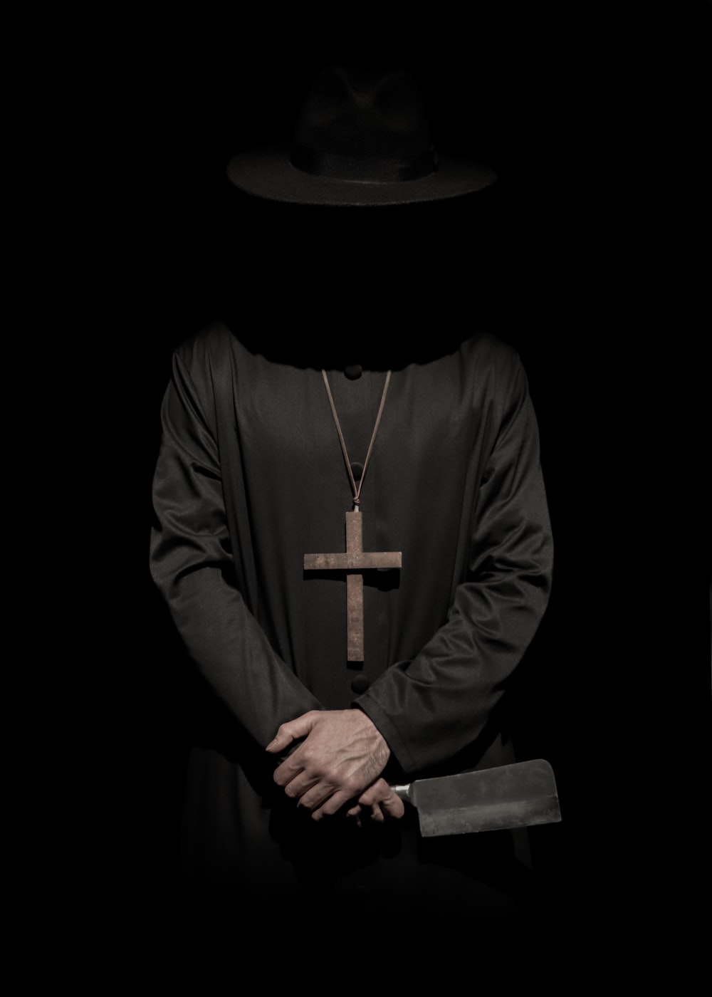 standing person wearing hat and cross necklace holding cleaver photo