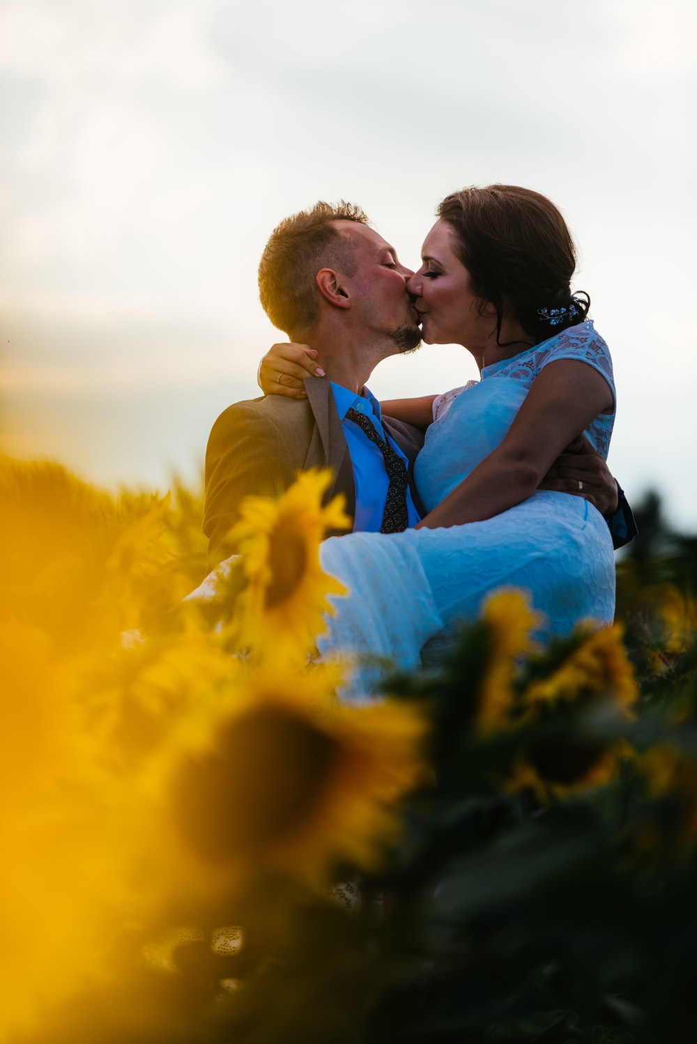 couple kissing in sunflower garden photo