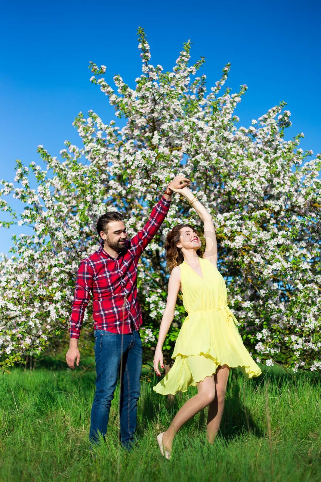 young beautiful couple in love dancing in blooming garden