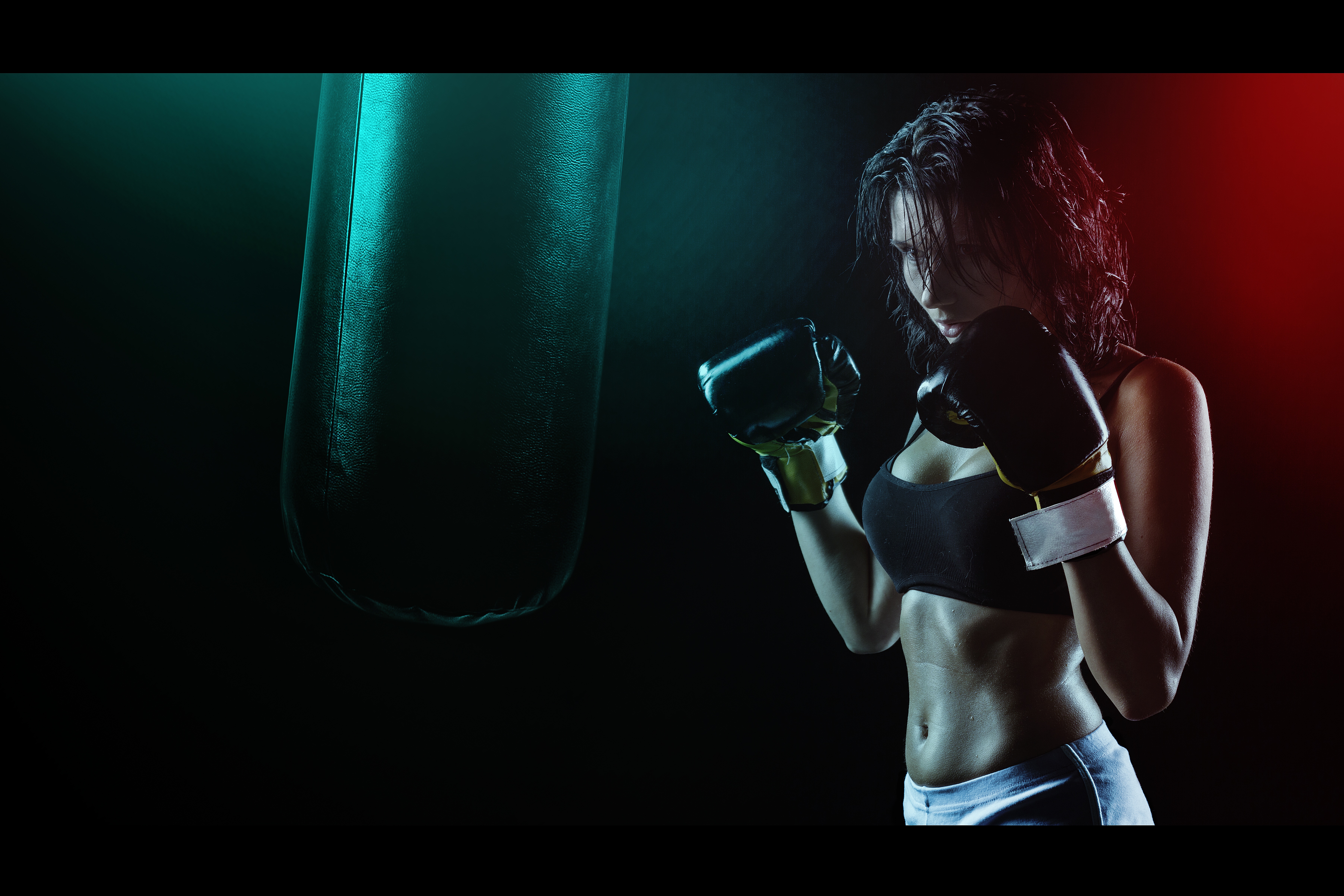 Woman in Boxing Gloves With Sports Bra Posing Boxing Style in Front of Punching Bag · Free