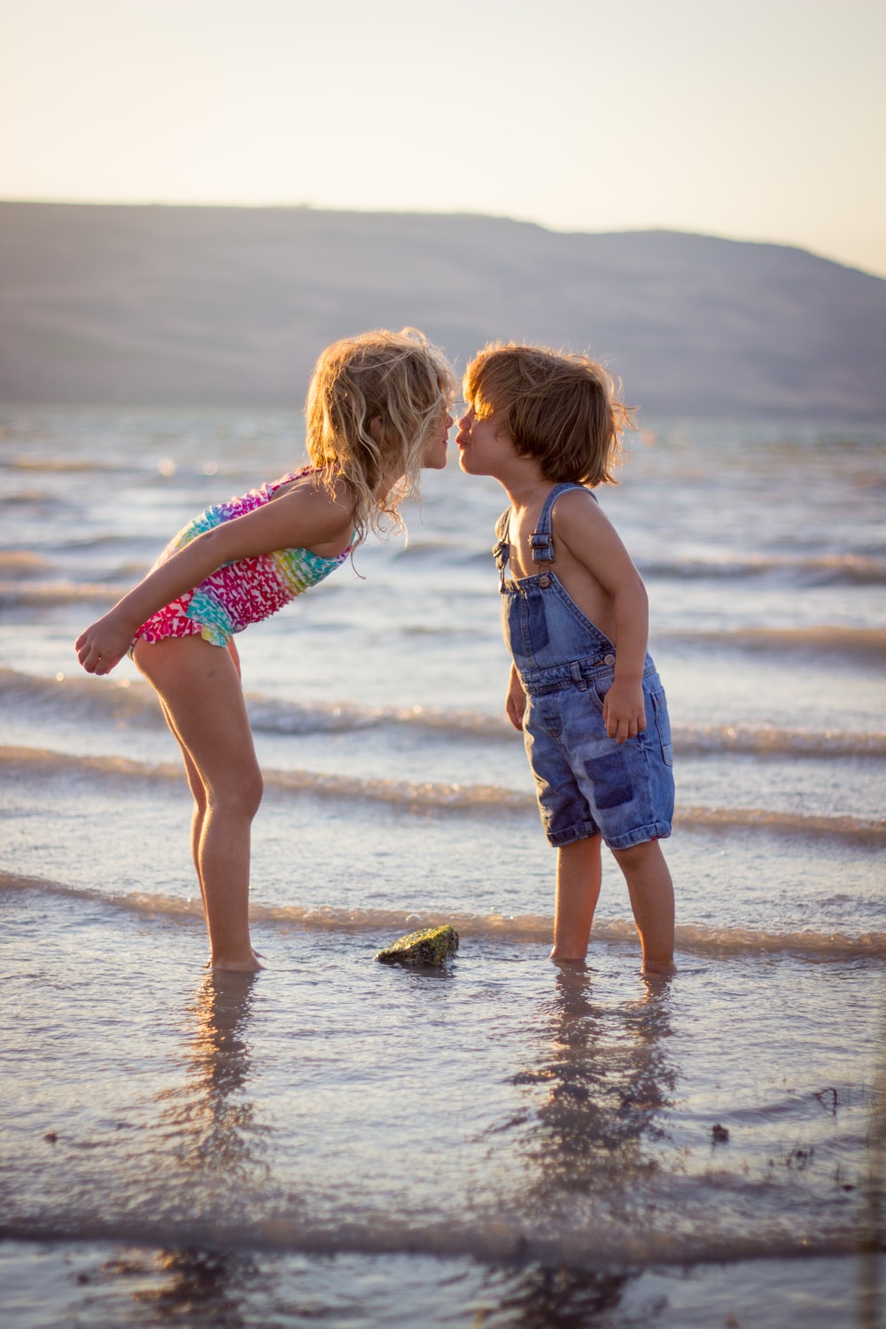 girl and boy kissing on beach during daytime photo