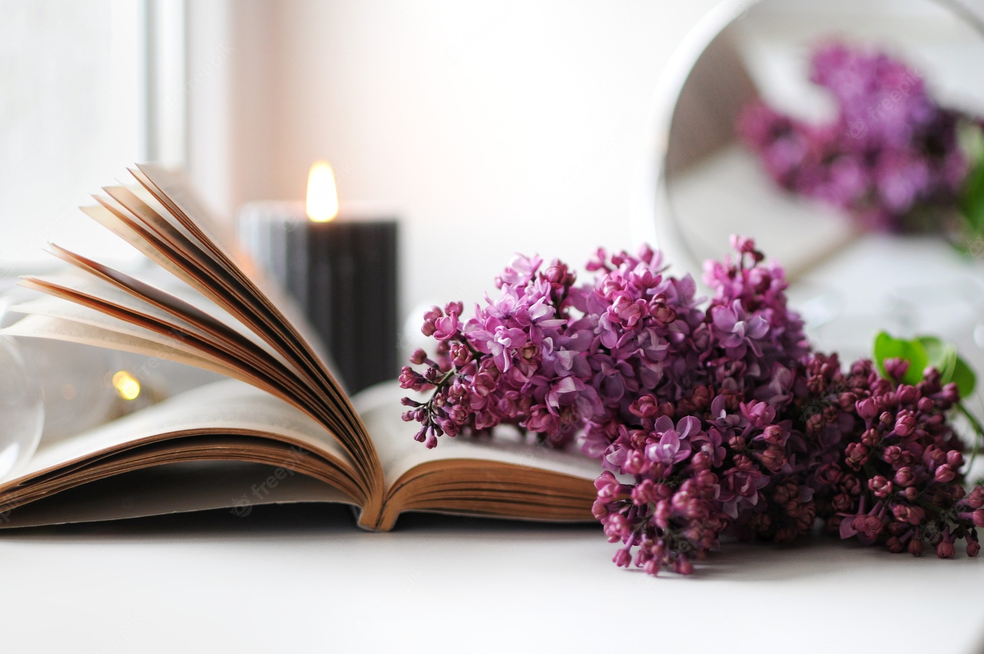 Premium Photo. Cozy spring atmosphere at home with lilac, book and candle. blooming lilac time