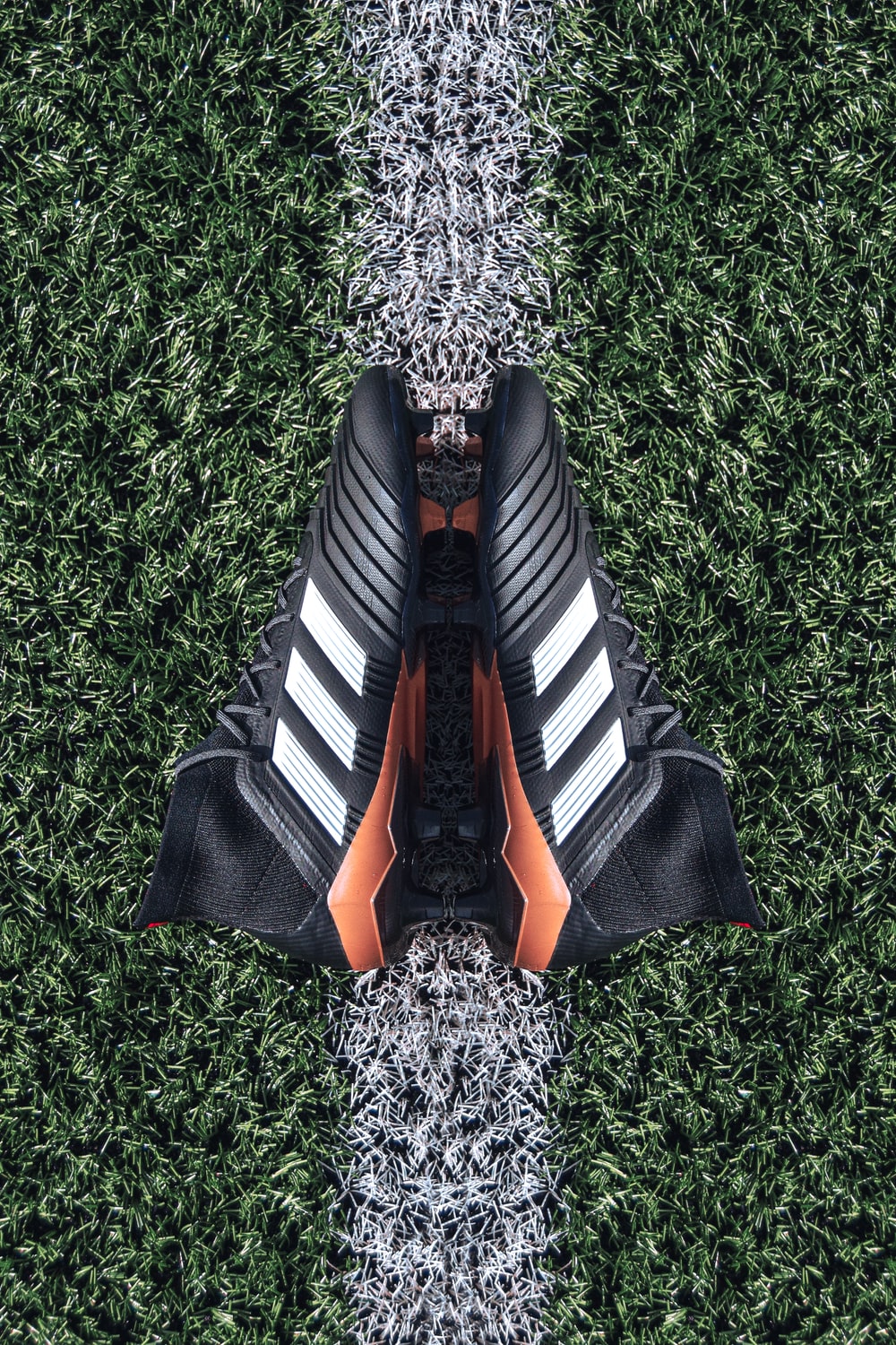 pair of black Adidas cleats on grass field photo