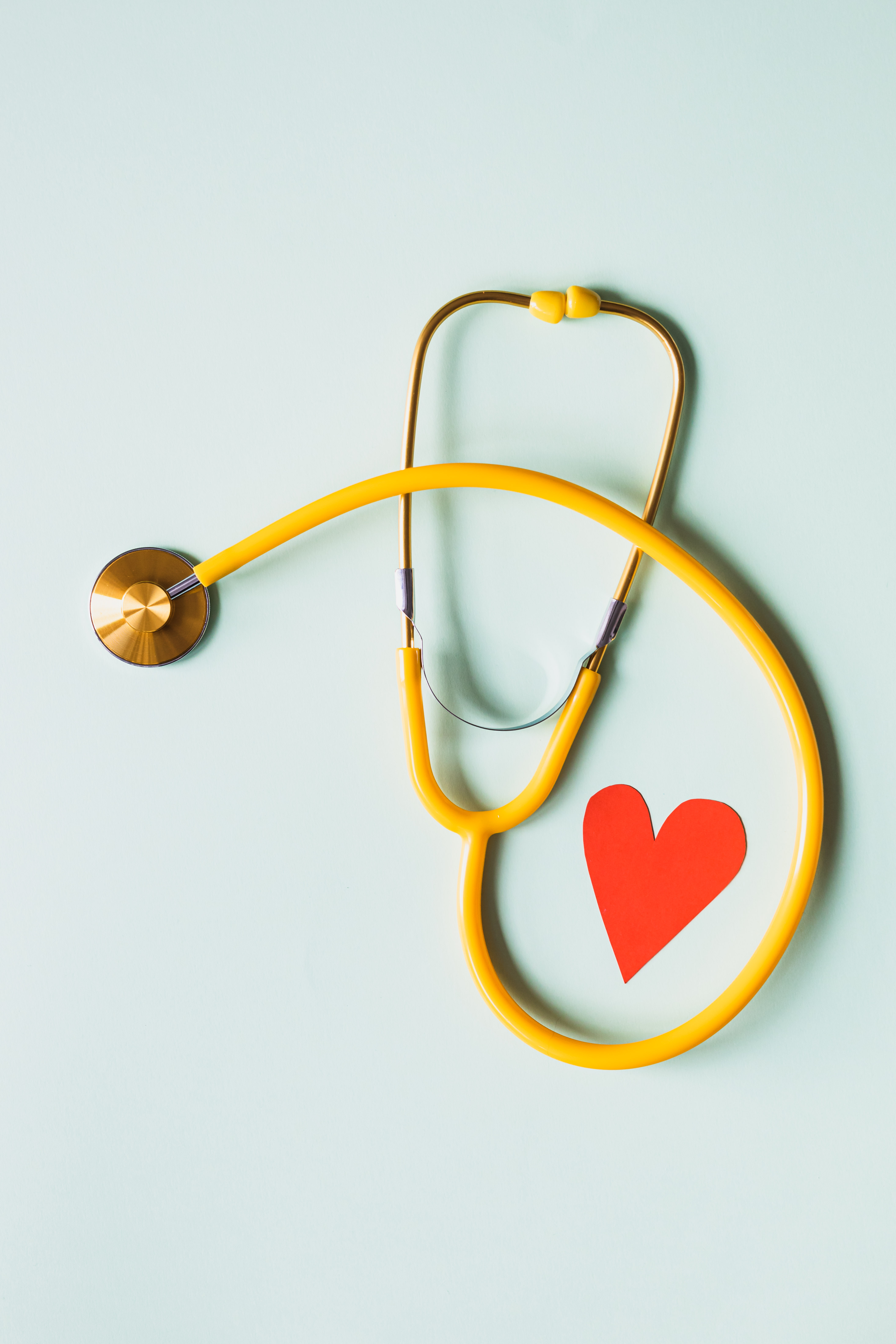 Medical stethoscope with red paper heart on white surface · Free