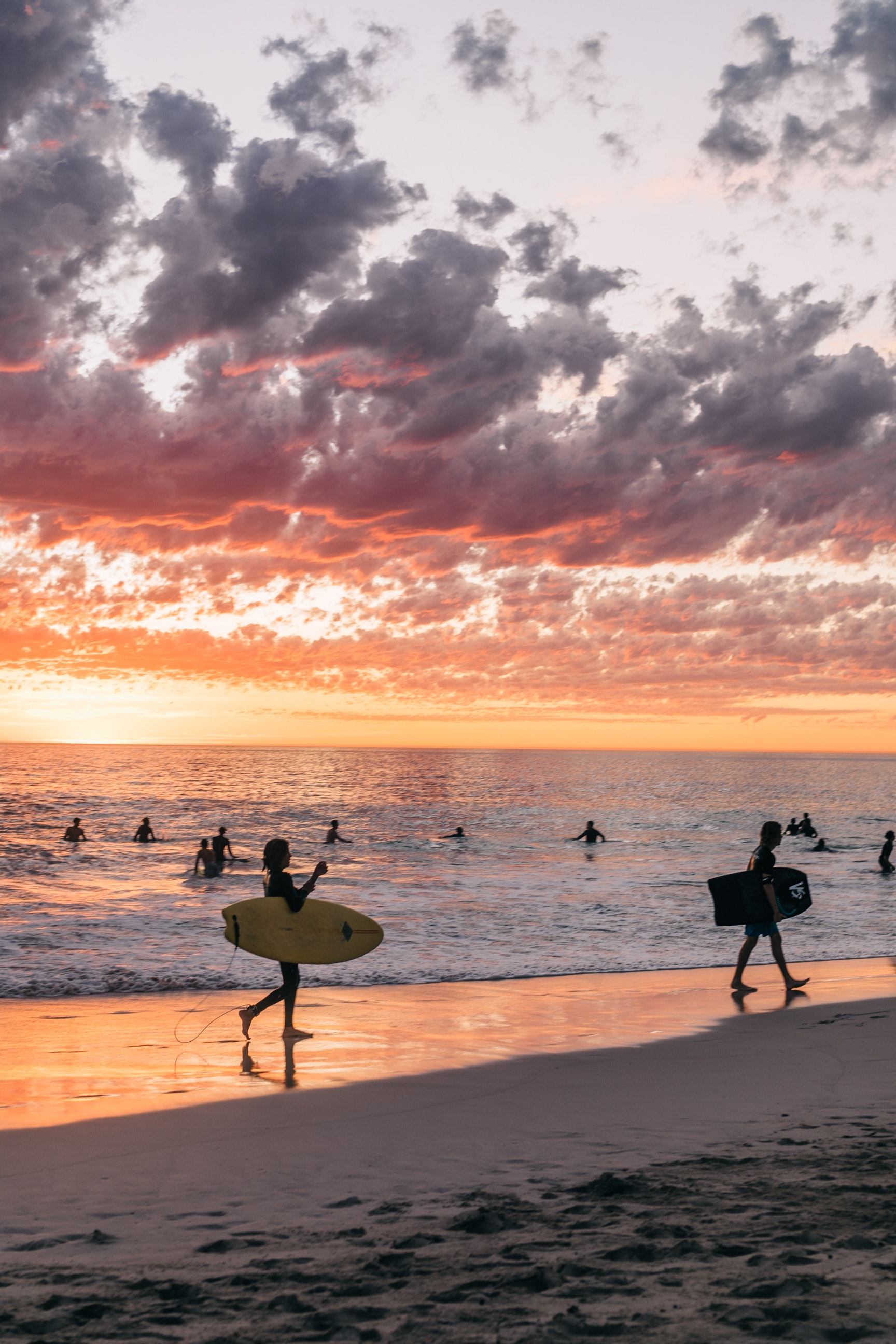 Unrecognizable people surfing at sundown on beach · Free