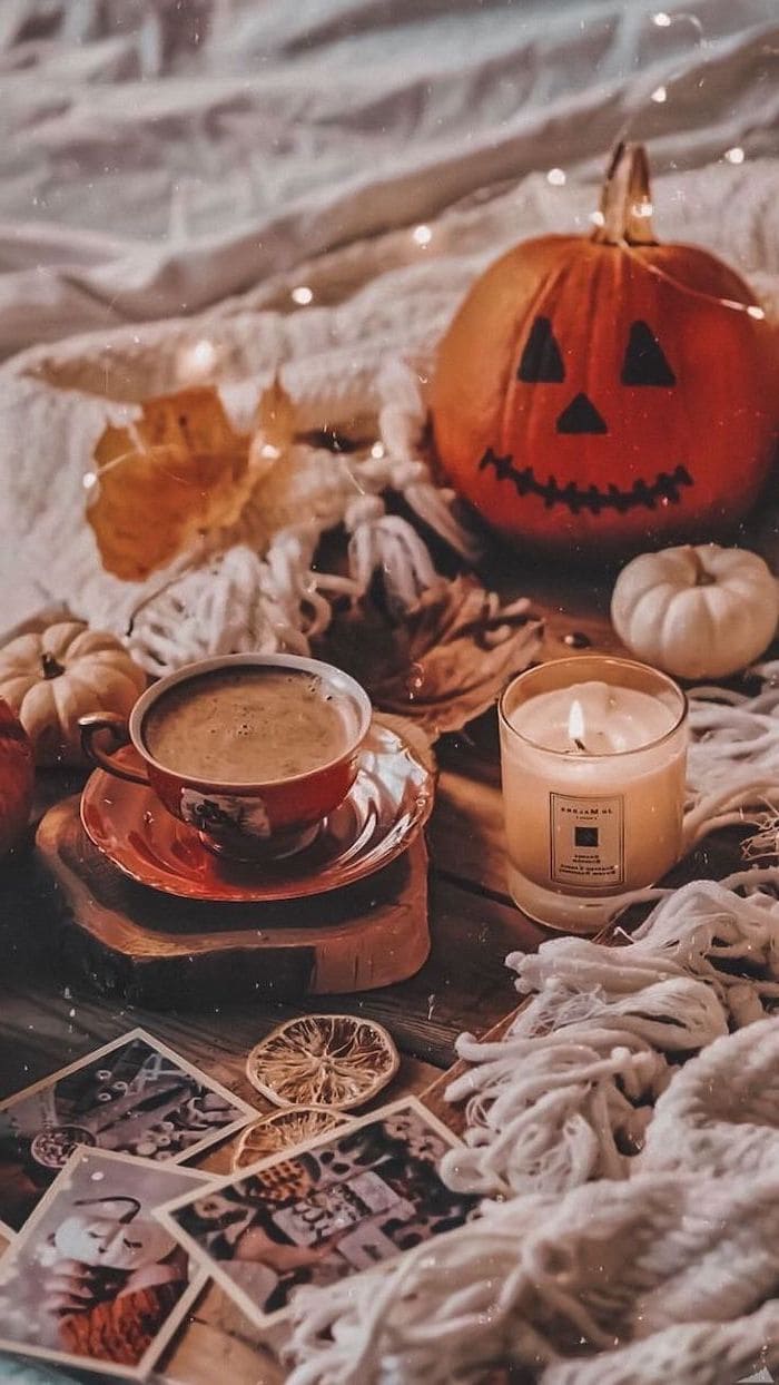 coffee cup next to lit candle carved pumpkin placed on wooden floor with white blankets aesthetic fall wallpaper, Best iPhone Wallpaper and iPhone background, WallpaperUpdate, Best iPhone Wallpaper and