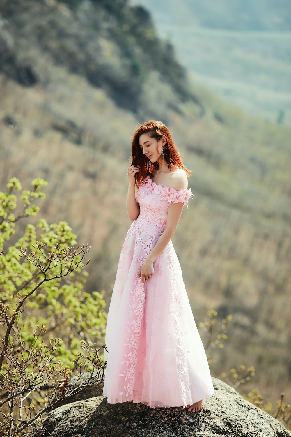 Woman wearing long dress poses leaning against a globe on a