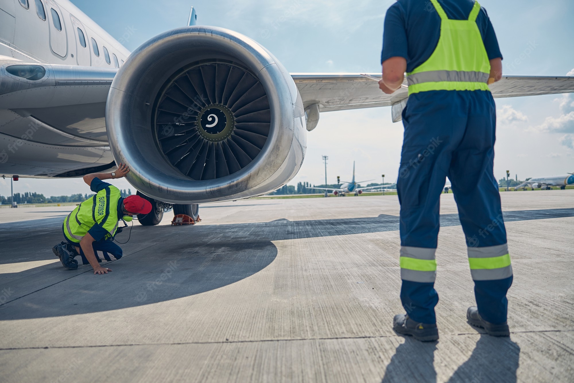 Premium Photo. Back view of two professional aircraft maintenance mechanics inspecting an airplane motor before the takeoff