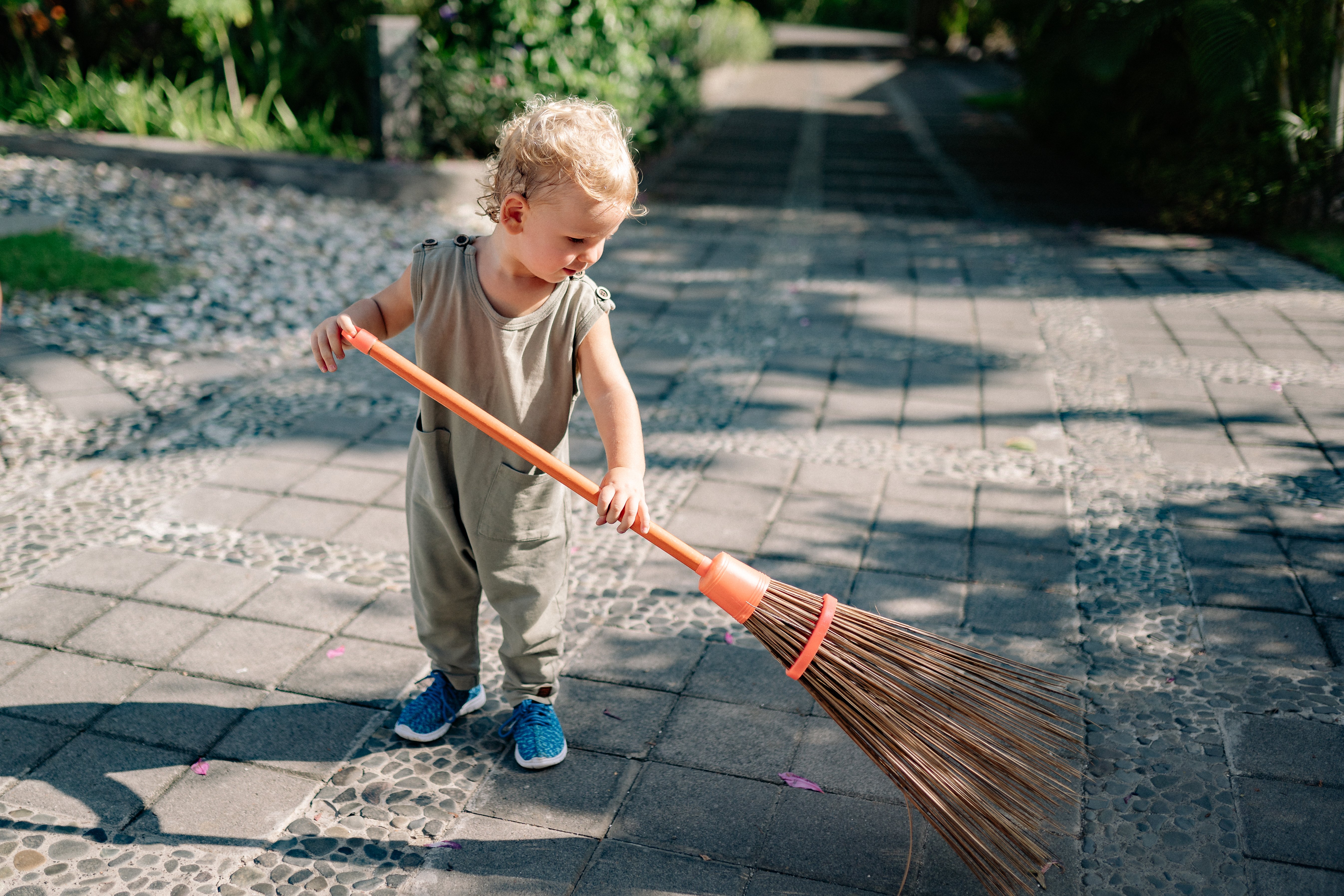 Charming Child Sweeping Concrete Pavement with Broomstick · Free