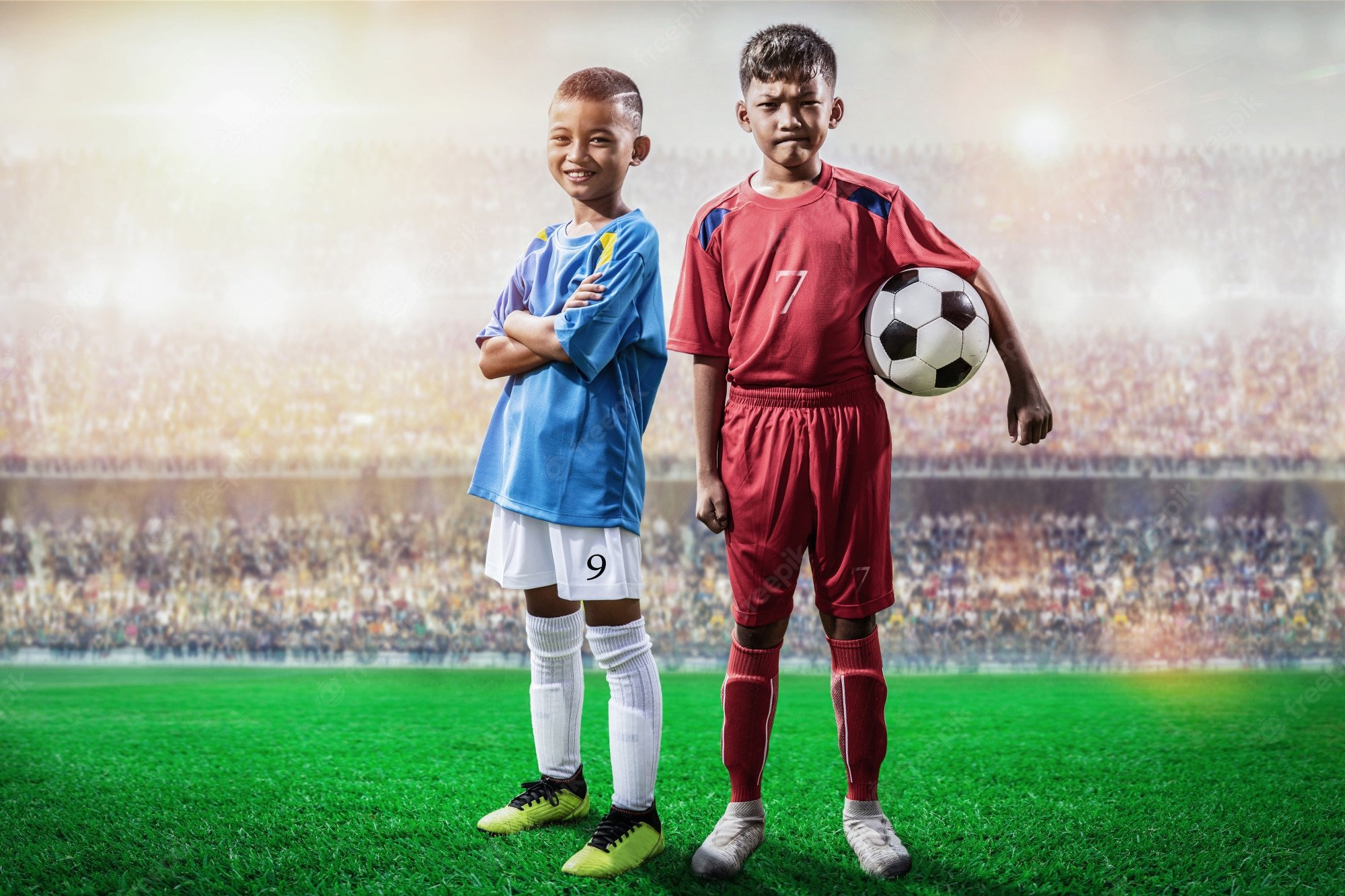 Premium Photo. Rival soccer kids player in blue and red jersey standing and pose to camera in the stadium