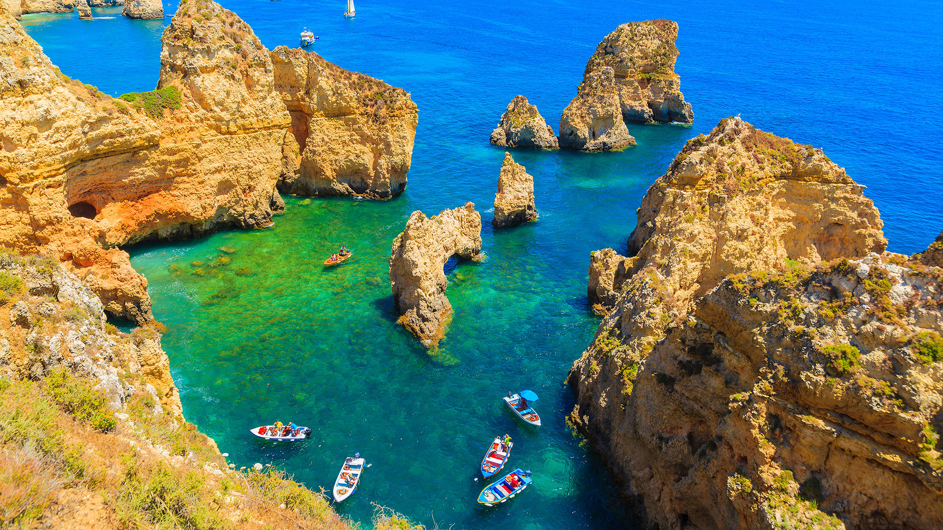Fishing boat on turquoise sea water at Ponta da Piedade, Algarve region, Portugal. Windows 10 Spotlight Image