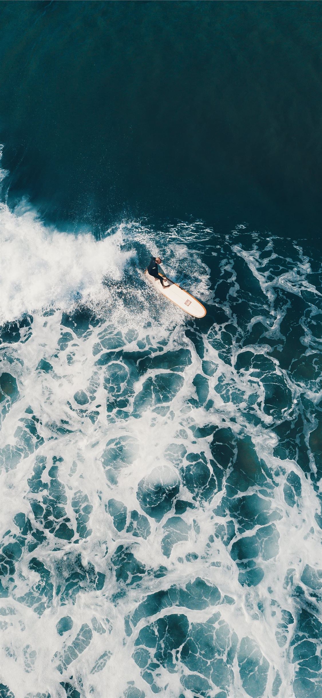 person surfing on sea waves during daytime iPhone X Wallpaper Free Download